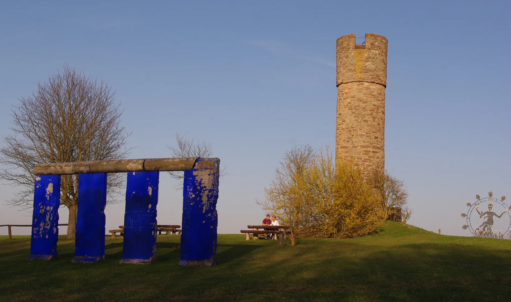 Photo showing: "Blaues Tor - West-Tor" in Niederlauer (J. Fell): Vier Originalteile der Berliner Mauer, ausgerichtet auf die Sonne zur Sommersonnenwende, aufgestellt wie Stonehenge. Berlin hatte die letzte funktionierende Stadtmauer. Entfernt man jedes zweite Mauerelement, entsteht ein Steinkreis. Die Skulptur wurde schon 1986 konzipiert. Im Hintergrund die wahrscheinlich größte aus Eisen gefertigte Shiva-Skulptur Europas