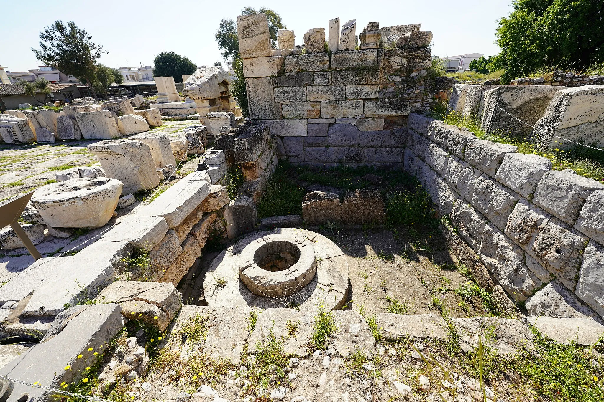 Photo showing: It is the well at which Demeter sat, when she was tired of searching her daughter Persephone.  Pausanias says that maidens of Eleusis performed dances around this well as part of sacred ceremonies. The structure of the well dates to the 6th-beginning of the 5th century BC, but the ancient structures are covered by later constructions dated to Roman times. The depth of the well is 6 meters and it inner side is constructed in the polygonal system of masonry.  The circular stones around the well probably functioned as seats for maidens who sat there chanting their hymns. The space was surrounded by an apsidal wall, destroyed in the 3rd century AD.