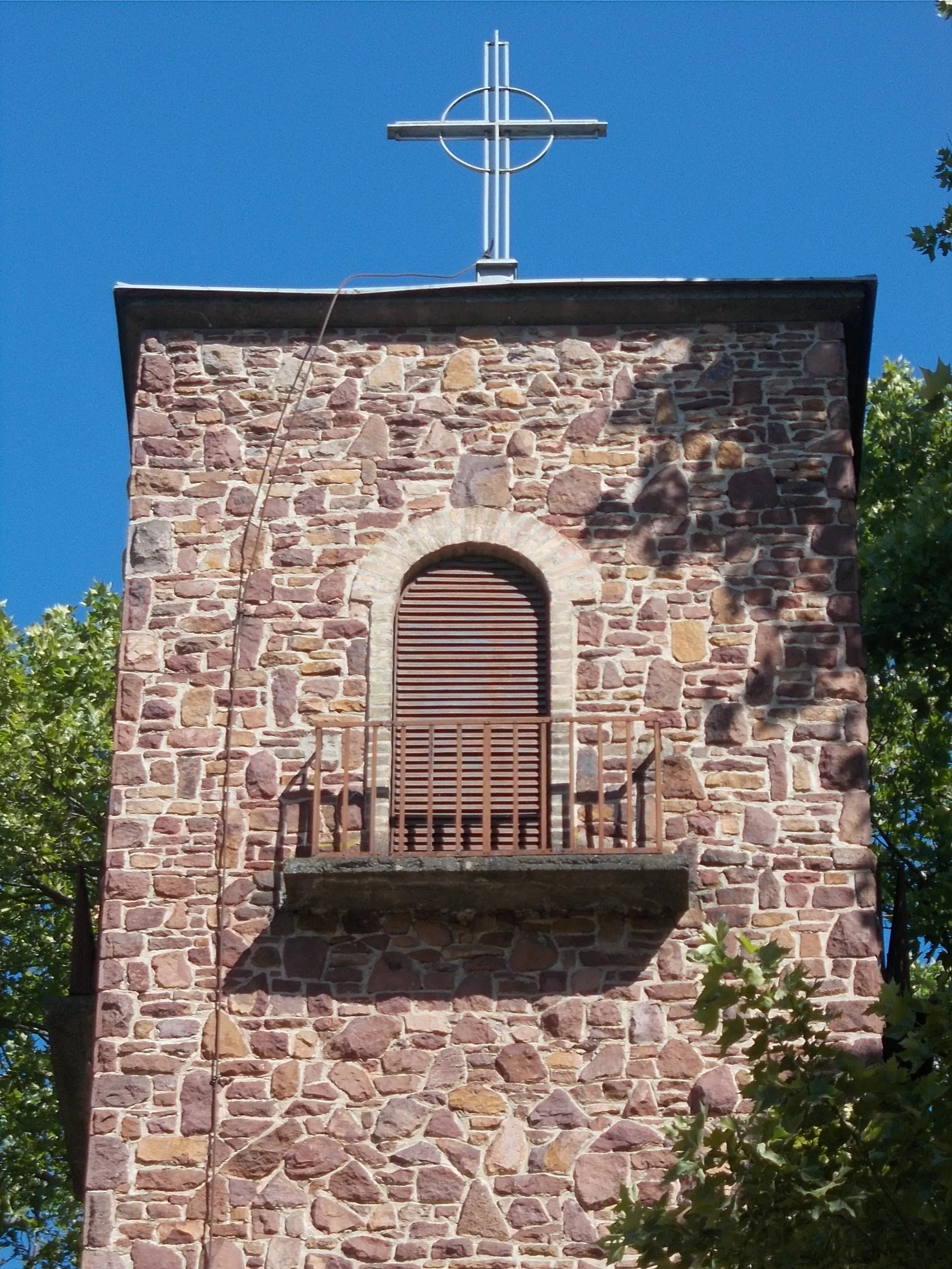 Photo showing: Holy Cross church tower balcony. Built in between 1941 and 1943/1944. Planned by László Irsay. So-called 'Ancient Christian' type, Romanesque Revival style, single nave church. Inside: some of its stainened glass windows (Painful Virgin, Saint Kinga and others) planned by painter Ferenc Deéd, made by Károly Majoros, Budapest glass painting master; the windows of the sacristyplanned by the sculptor Béla Szappanyos. The wrought iron altar made by Ferenc Farkas. Also inside is a Saint Taddeus wooden statue by Barnabás Búza. Frescoes: made by József Przudzik: Pope John Paul II (1994) and the Arc before sacristy - Széchenyi tér, Balatonföldvár, Somogy County, Hungary