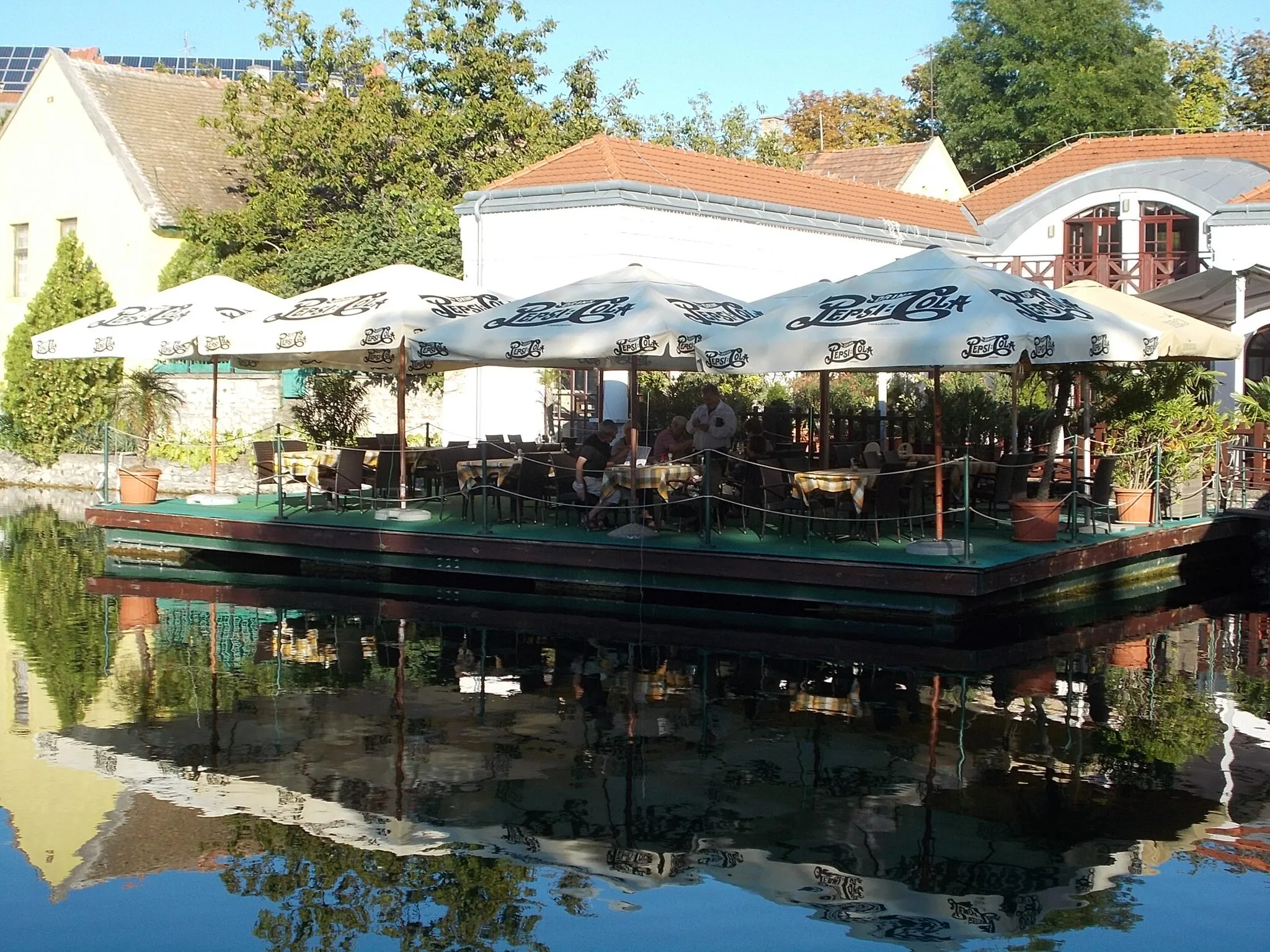 Photo showing: Listed former bath. Pepsi ad parasols on Café terrace - Mill Lake or Big Lake, Lake District, Tapolca, Veszprém County, Hungary.