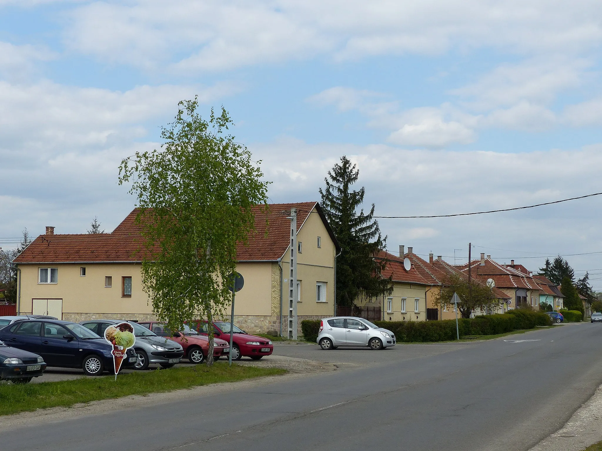 Photo showing: Petőfi tér (parkoló autók), Szent Imre utca az első ház ill. attól jobbra. A felvétel 2017. április 24-én készült Bagon, Magyarországon.