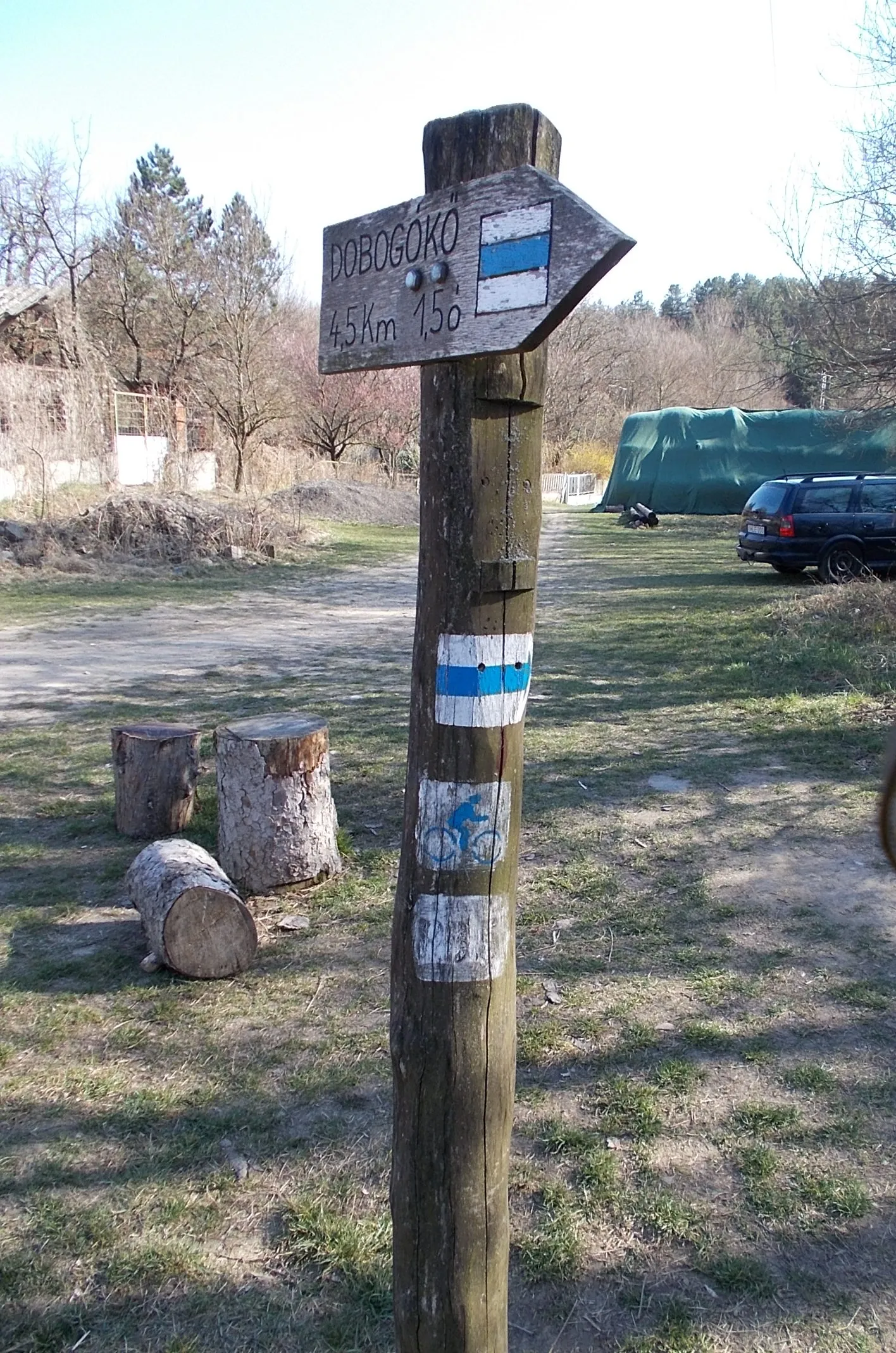 Photo showing: Countrywide Blue Tour (abbr. OKT) section 15 /subsection OKT-152/ blue mountain bike trail, directional sign toward Dobogókő - close to a footbridge over Kanyargos Creek (Kovács Creek), Pilisszentkereszt, Pest County, Hungary.