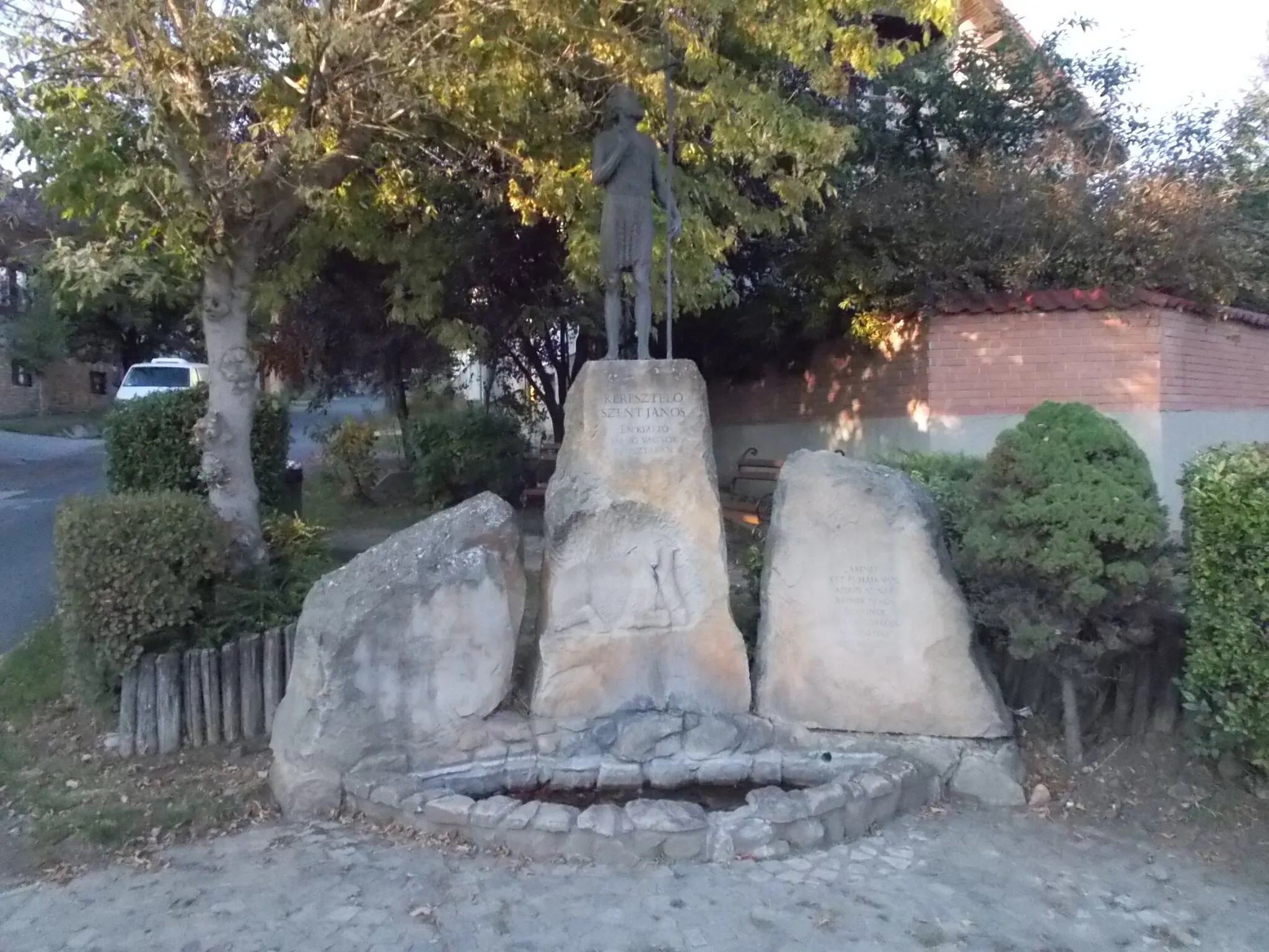 Photo showing: John the Baptist, the Forerunner of Our Lord by Dávid Tóth (2002 bronze statue, stone relief, fountain). St. John stands on a rock. Water flows (not on this pic) from the mouth of a lamb carved from the rock. At Petőfi Street and Rákóczi Street corner, Verőce, Pest County, Hungary.