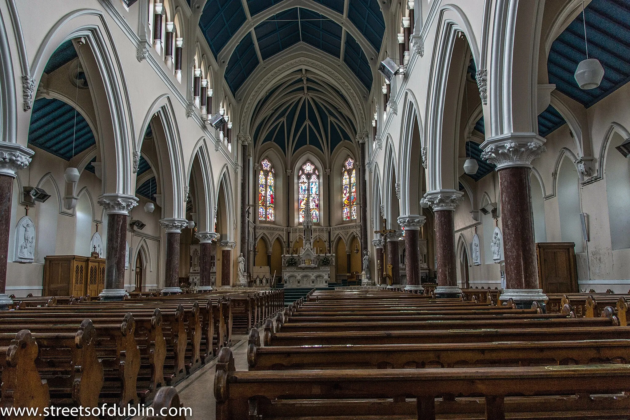 Photo showing: A site for a new church was bought at Broomwood, Monkstown, from the family of James Doherty.  Two of the finest windows in the church are dedicated to the memory of the Doherty family. In 1861, the foundation stone for the present church was laid and was dedicated to St Patrick.  It was the last of 5 churches commissioned by the same parish priest, Canon Sheridan, in the parish of Kingstown, but he died before completion.  The new Parish Priest decided to change the plans, and commissioned George Ashlin to draw up new plans.  The builder was Michael Meade.  The tender price, excluding the spire, was £5,750.