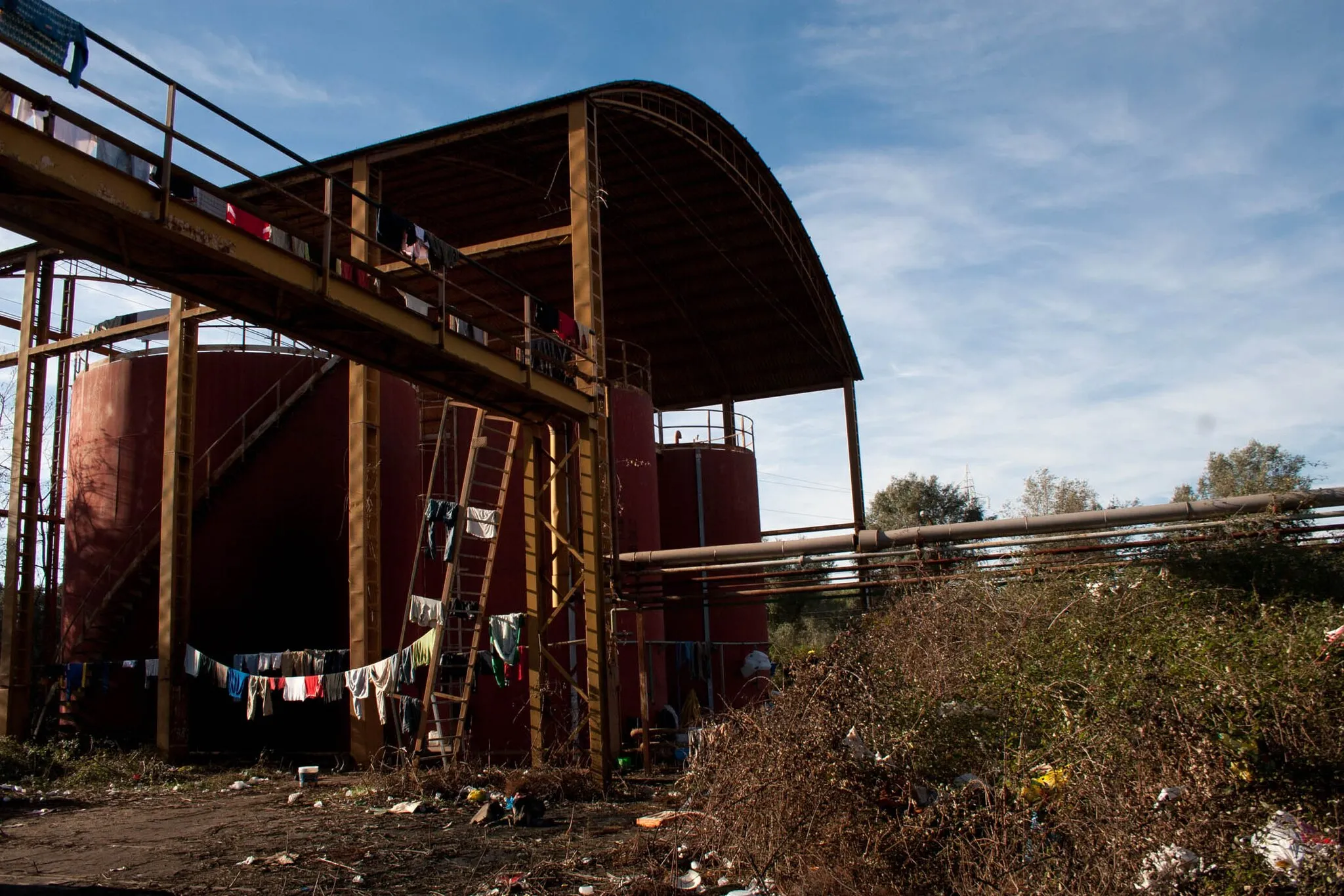 Photo showing: Fino agli scontri del 7 gennaio 2010 l'ESAC, ex Opera Sila, ARSSA era lo stabilimento diventato la più grande baraccopoli per i lavoratori stagionali delle campagne tra Rosarno e Gioia Tauro. Questo "ruolo" era prima affidato alla Cartiera, andata però in fumo e poi murata nell'agosto del 2009. Le condizioni di vita degli abitanti erano pessime. Secondo Medici Senza Frontiere, che per anni hanno seguito i lavoratori stagionali in Calabria, gli africani arrivavano qui in buone condizioni di salute per poi ammalarsi qui cronicamente.
30 dicembre 2009

www.andreascarfo.com