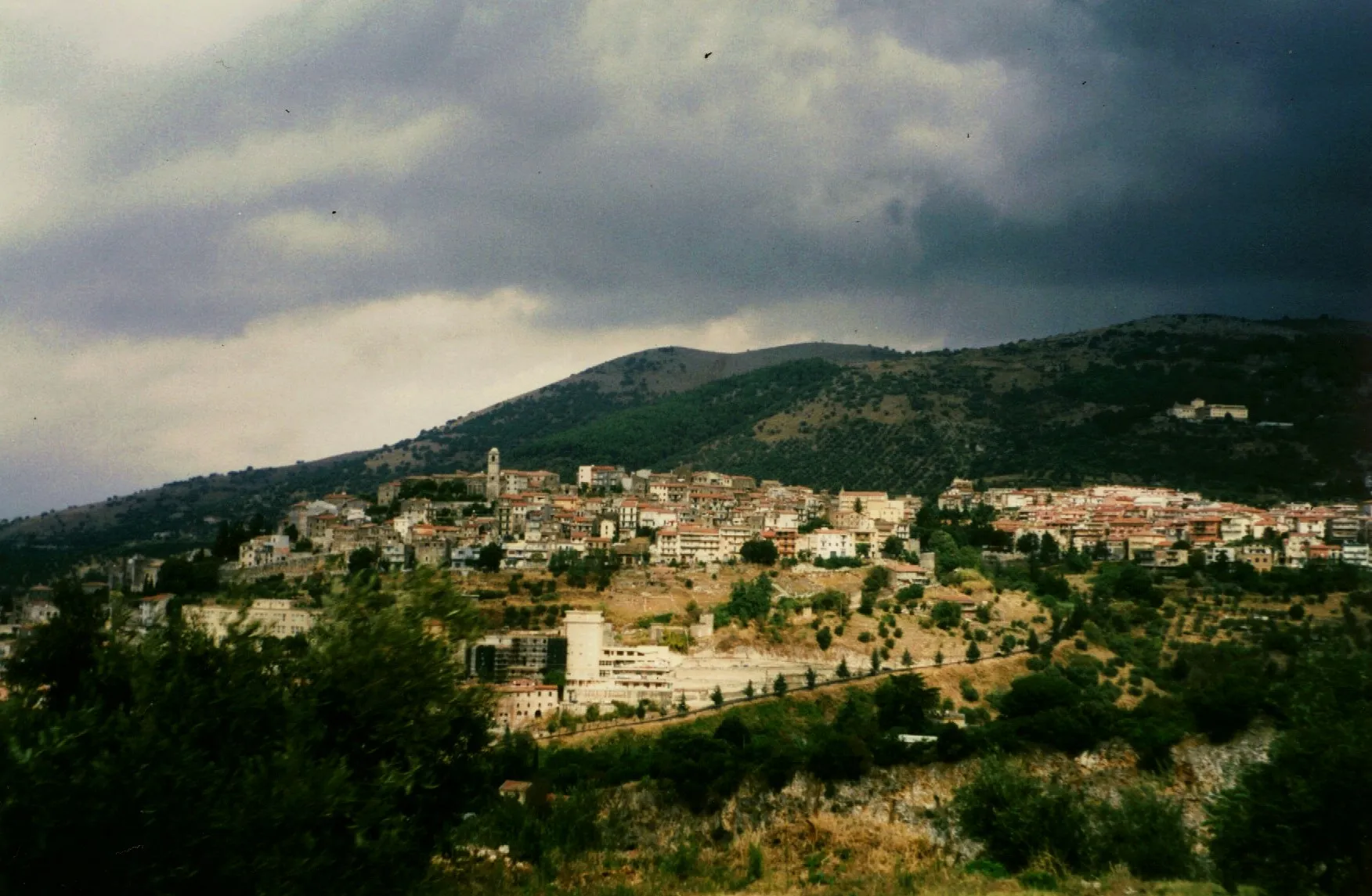 Photo showing: Photo of town centre from a ringing road. The village monastery is visible in the top right of the photo, watching over the town from its elevated perch on the mountain.