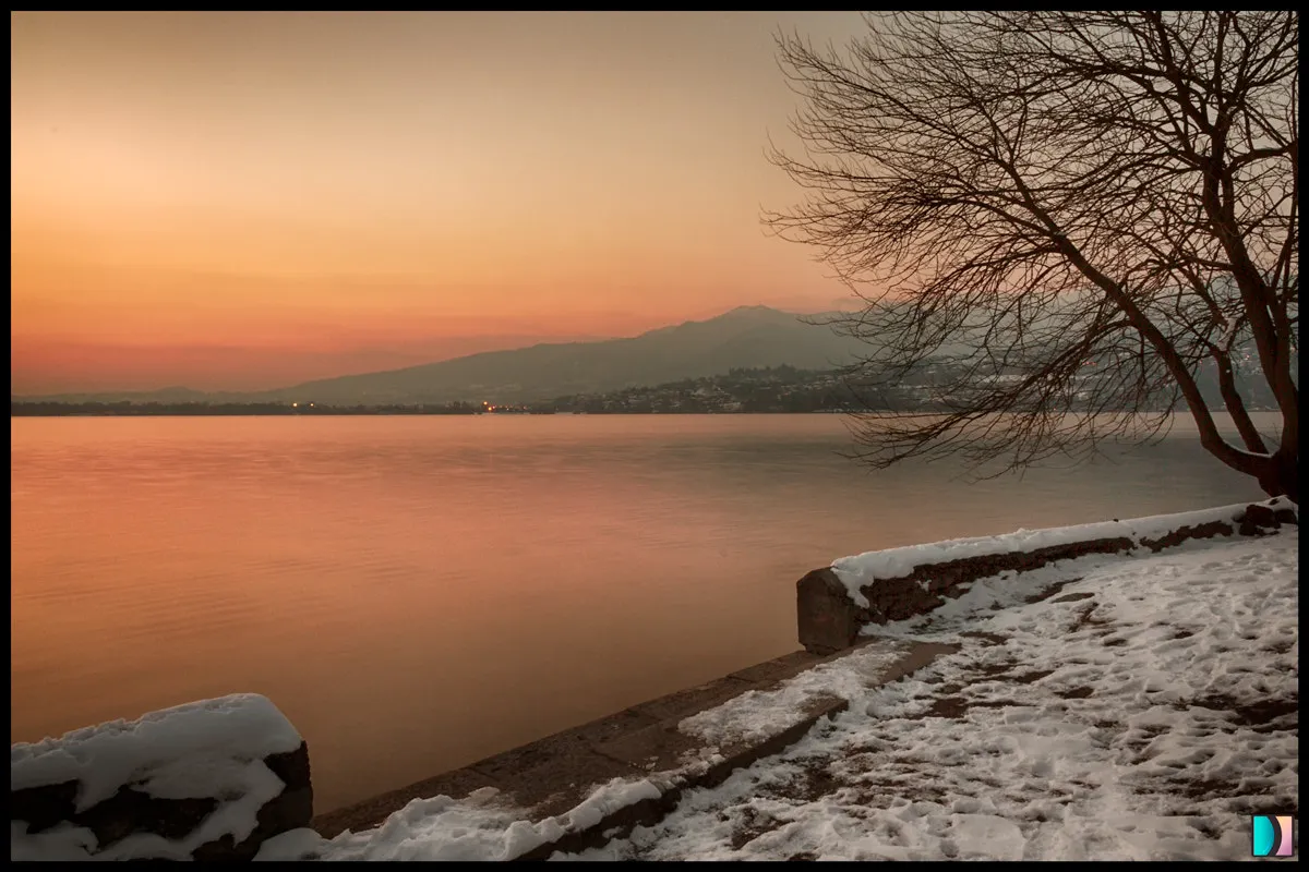 Photo showing: 500px provided description: Pusiano lake at sunset. [#lake ,#winter ,#water ,#tree ,#branch ,#golden ,#snow ,#emidellizuani]