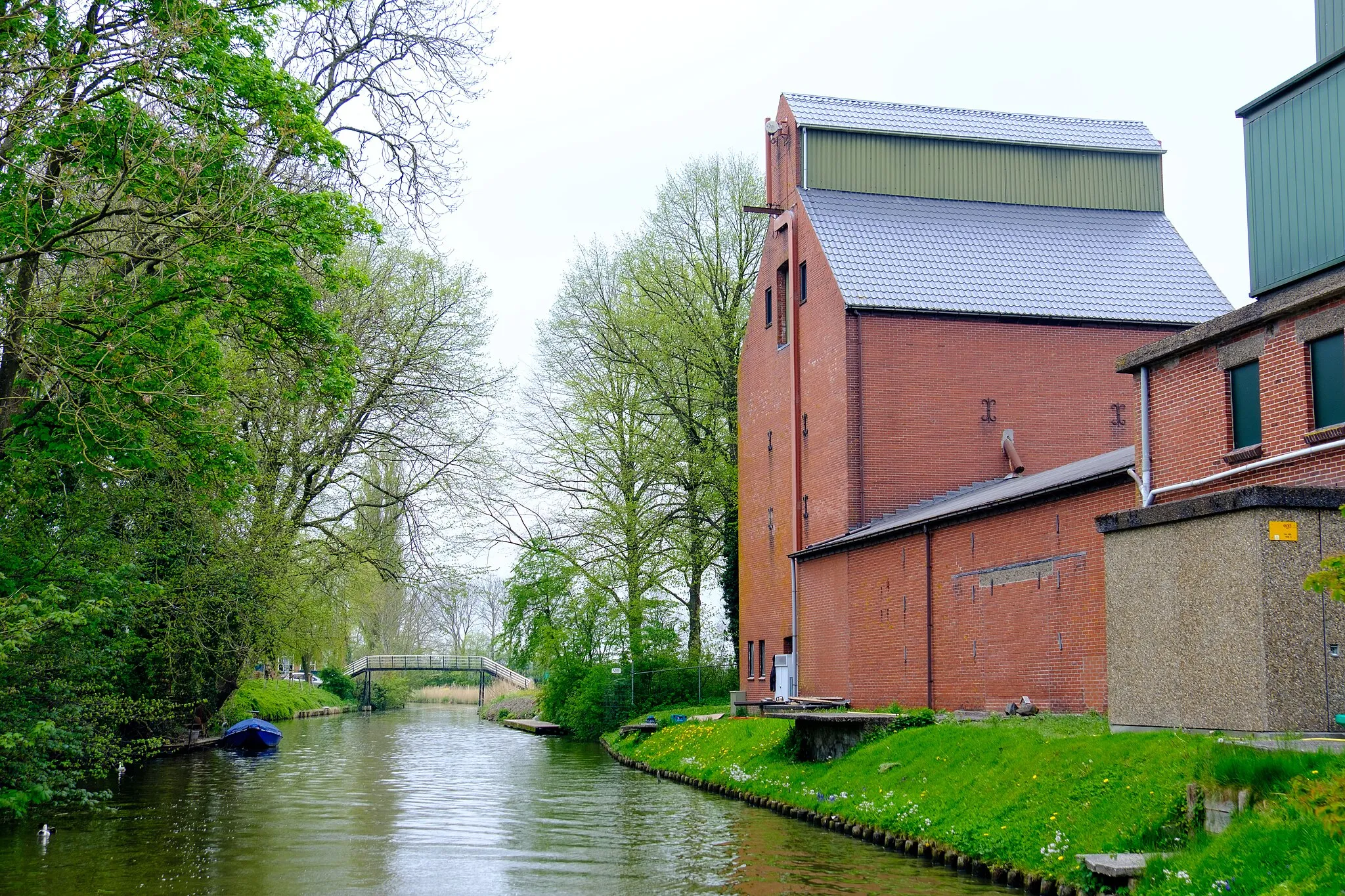 Photo showing: Voormalige veevoederfabriek van Jacobus Jan Nienoord aan het Kanaal Baflo-Mensingeweer in Baflo met op de achtergrond het hoogholtje tussen Baflo en Rasquert