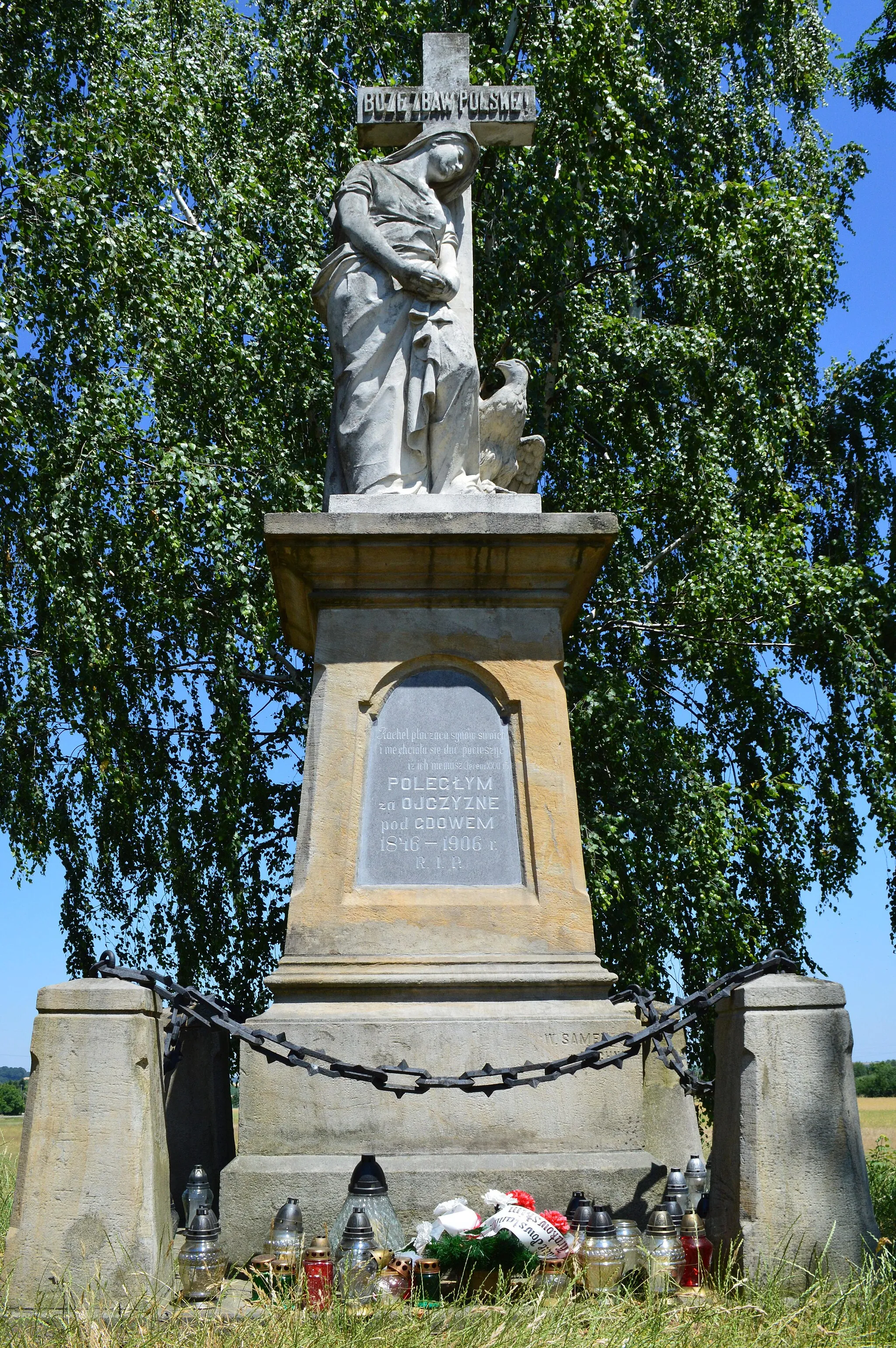 Photo showing: Gdów Cemetery ("Cmentarz") is adjacent to the field where the historic Battle of Gdów took place on 26 February 1846 and in which Polish 'insurgents', under the command of the absent Colonel Suchorzewski, fought for independence from Austria in the only battle of the Kraków Uprising.  This Uprising had been organized as integral to a more widespread campaign which included the Greater Poland Uprising (1846) against the imperial forces of the partition authorities of Austria, Prussia and Russia.  The Peasant Uprising  of 1846 was encouraged by the Austrians to counter the efforts of the ‘insurgents’ and the peasants aided the Austrian forces both in the slaughter of the battlefield and in the subsequent pursuit of the supporters of the Polish nationalists.  On top of a mound in the corner of the Cemetery is a poignant monument to the 154 ‘insurgents’ who were killed during the battle and were buried in three pits in the field before being interred together under the mound in 1906.
Father Ludwik Kusionowicz, the parish priest in Gdów from 1842 and who later became Dean of Wieliczka, chronicled the Battle of Gdów and also provided refuge for some supporters of the Polish nationalists who were fleeing the Austrian military and their peasant militia.   Ludwik’s "nephew" Sylwester was at that time living in Chochołow and training as a teacher and organist under Jan Kanty Andrusikiewicz (pl) who was one of the leaders of the Chochołow Uprising (pl) which took place on 21 February 1846, five days before the  Battle of Gdów.  Around 1850 Sylwester moved to Gdów to run the first 'state school' in the district (in the former parish school building) and in spite of the efforts of the Austrian authorities to suppress Polish culture in Galicia it continued classes in the Polish language beyond the period of the January Uprising (1863-1864) which extended across the lands controlled by the Russian Empire to the outskirts of Kraków.  Sylwester, who was father to a number of children, including Józef, Władysław and Andrzej, was also the organist at the Church and around 1860 moved into the old church house (to #39 from house #37).  Sylwester Kusionowicz is buried alongside the Cemetery Chapel, where his "uncle" Ludwik was later buried, in a prominent grave watched over by a beautiful statue of Mary sculpted by Edward Stehlik (pl).
The mound on which the '1846 Monument' was erected was created over a number of years by members of the local fire brigade and it was under the third president of the Gdów brigade, Szymon Boguta, that the mound was completed and the monument dedicated.  Szymon was also the organist at the Church of Gdów and was married to Walerja Kusionowicz, daughter of Sylwester.

The Scotch Mist Gallery contains many photographs of historic buildings, monuments and memorials of Poland.