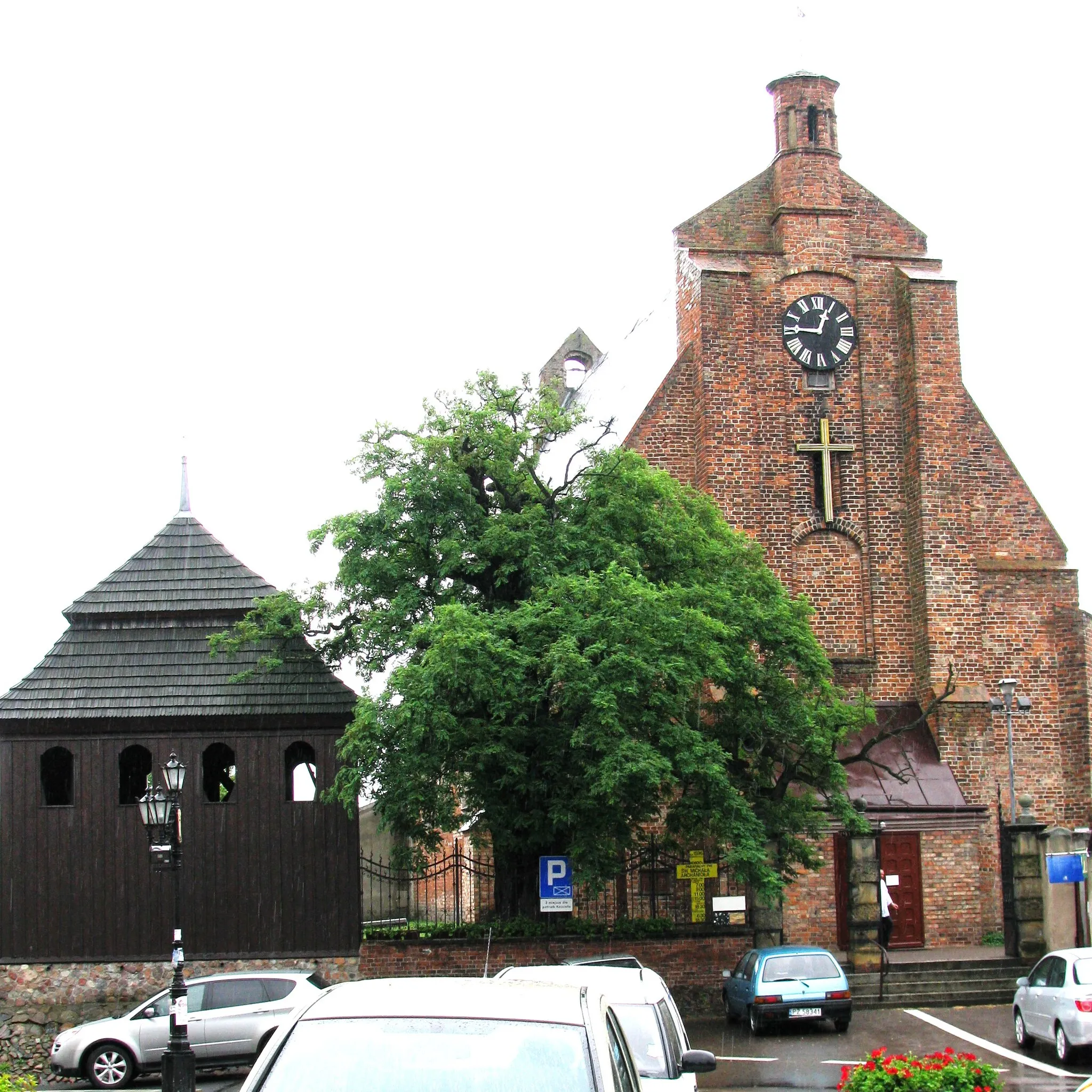 Photo showing: Church of the Archangel Saint Michael, Pobiedziska, Poland.  The church is close to the Rynek and dates from the thirteenth century, with the adjacent wooden bell tower dating from the nineteenth century. The Scotch Mist Gallery contains many photographs of historic buildings, monuments and memorials of Poland.