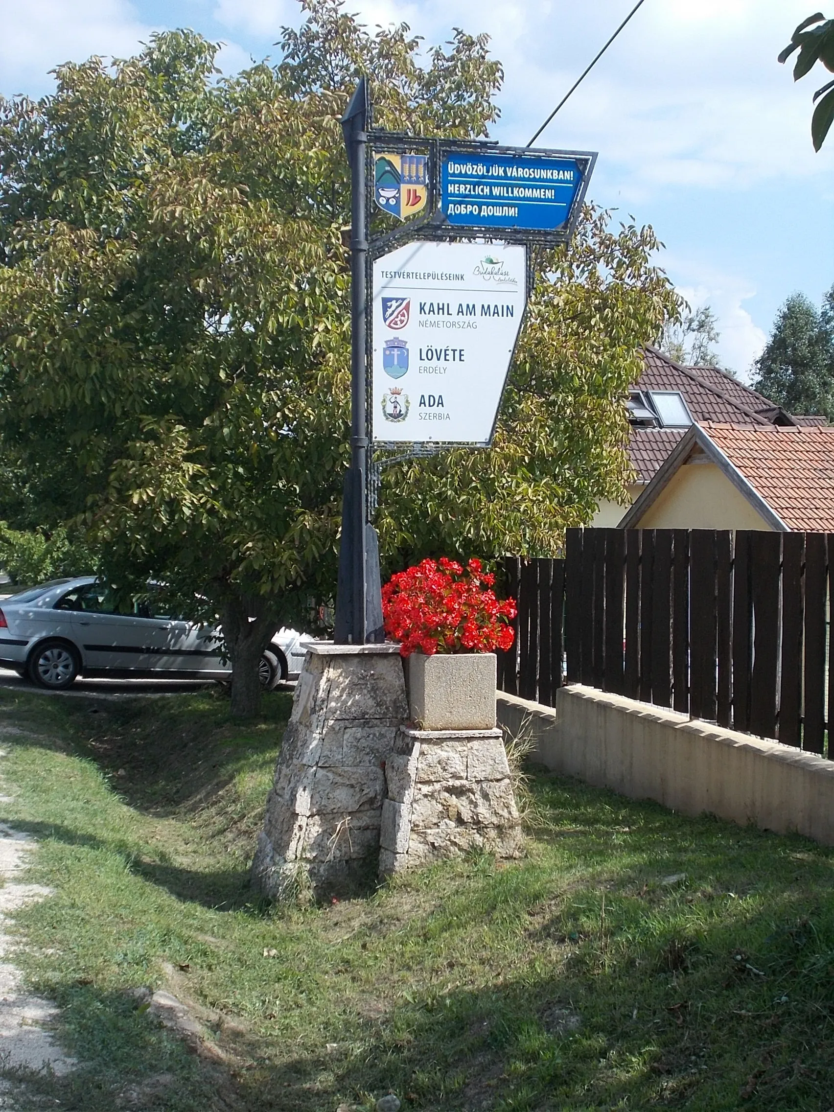 Photo showing: Column with names of twin towns:  Ada, Serbia; Kahl am Main, Germany; Lueta, Romania; AND trilingual welcome sign - Damjanich Street, Budakalász, Pest County, Hungary.