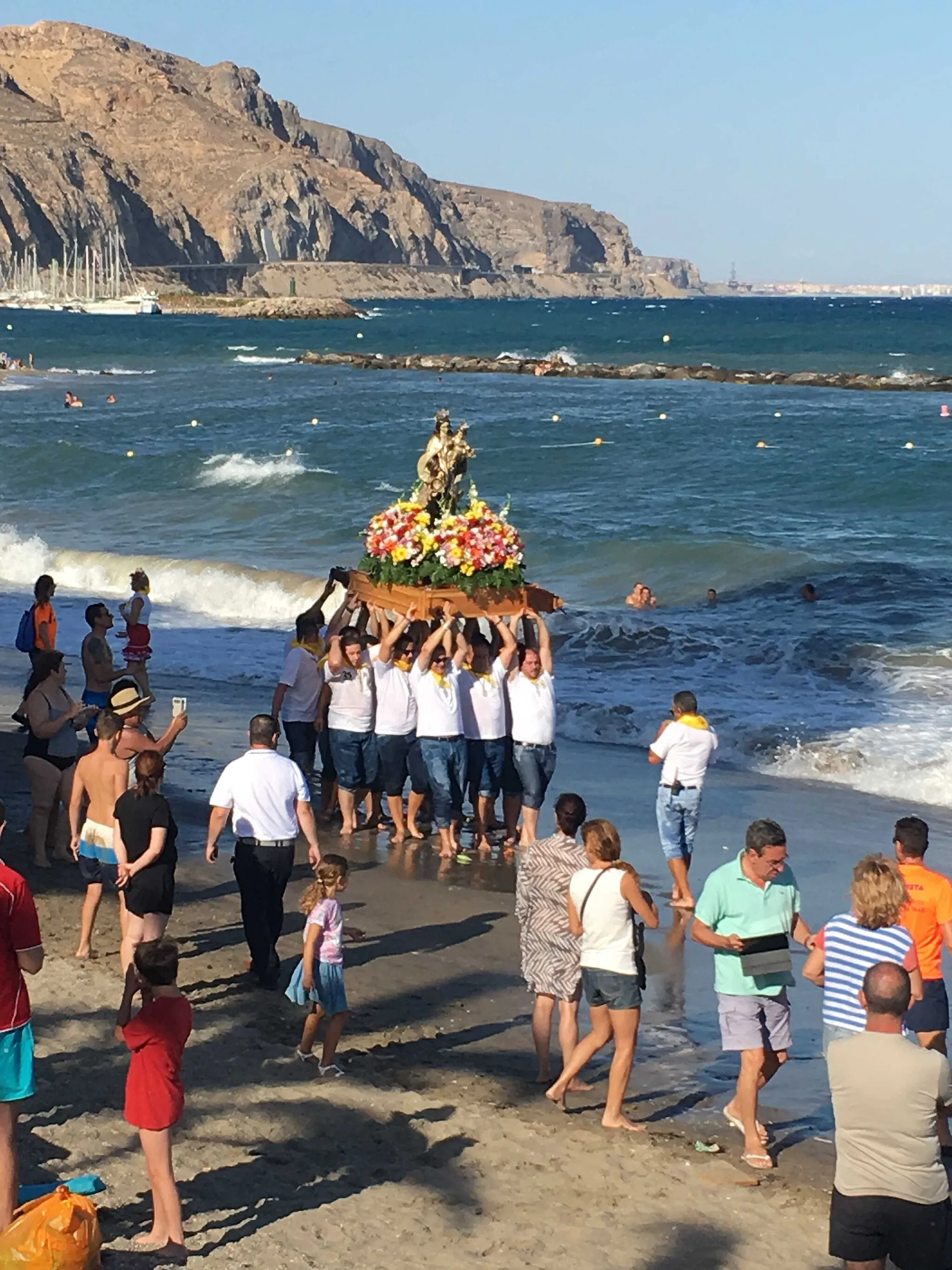 Photo showing: La procesión marítima se suspendió pero la Hermandad de la Virgen del Carmen de Aguadulce hizo la procesión con un recorrido alternativo por el Paseo Marítimo y la orilla de la playa, lo que dejó imágenes para el recuerdo de las fiestas de este año.
Tras la procesión se celebró la Santa Misa en la explanada del Puerto Deportivo, al lado de la Torre de Control, en la que hubo un recuerdo especial para las víctimas del atentado de Niza y para el padre del Obispo de Almería, recientemente fallecido. Cientos de vecinos acudieron a esta eucaristía y acompañaron a la Virgen en el itinerario de regreso. La Misa estuvo cantada por el Coro Salinero Virgen del Rosario y la procesión contó con la compañía de la Unión Musical Roquetas de Mar.