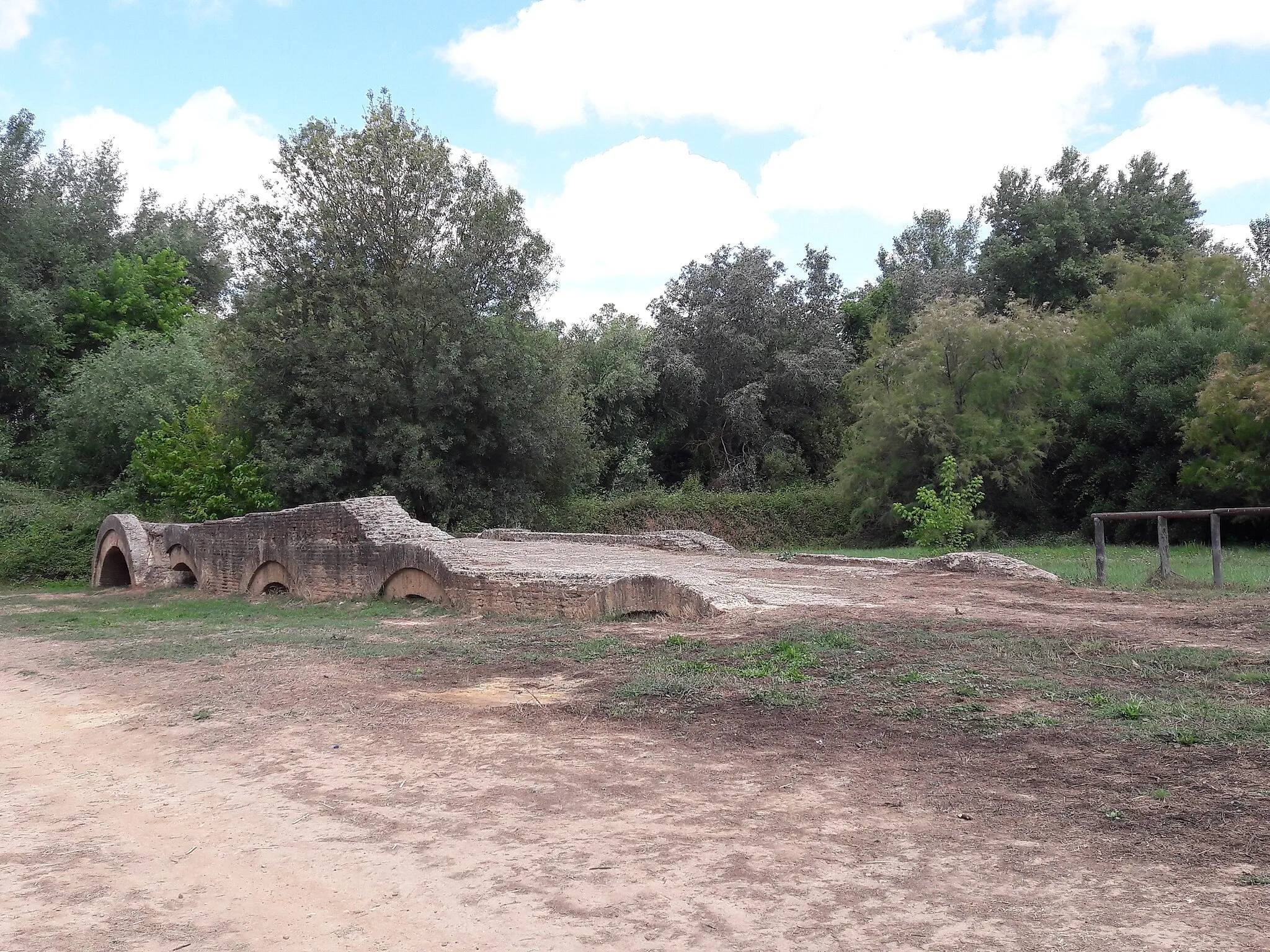 Photo showing: Restos del puente romano del corredor verde del río Guadiamar en Aznalcázar. Único puente existente sobre el río Guadiamar en el s. XVI, fue relevante por la necesidades de comunicación entre Híspalis (Sevilla) y Onuba (Huelva). Posiblemente date de épocas muy anteriores que pudieran ser islámicas e incluso tardo romanas o propiamente romanas. Hundido parcialmente, aún quedan varios arcos visibles de los catorce que existían. El curso del río fue desviado, y hoy en día se encuentra dentro de los terrenos del Paisaje Protegido del Corredor Verde del Guadiamar.