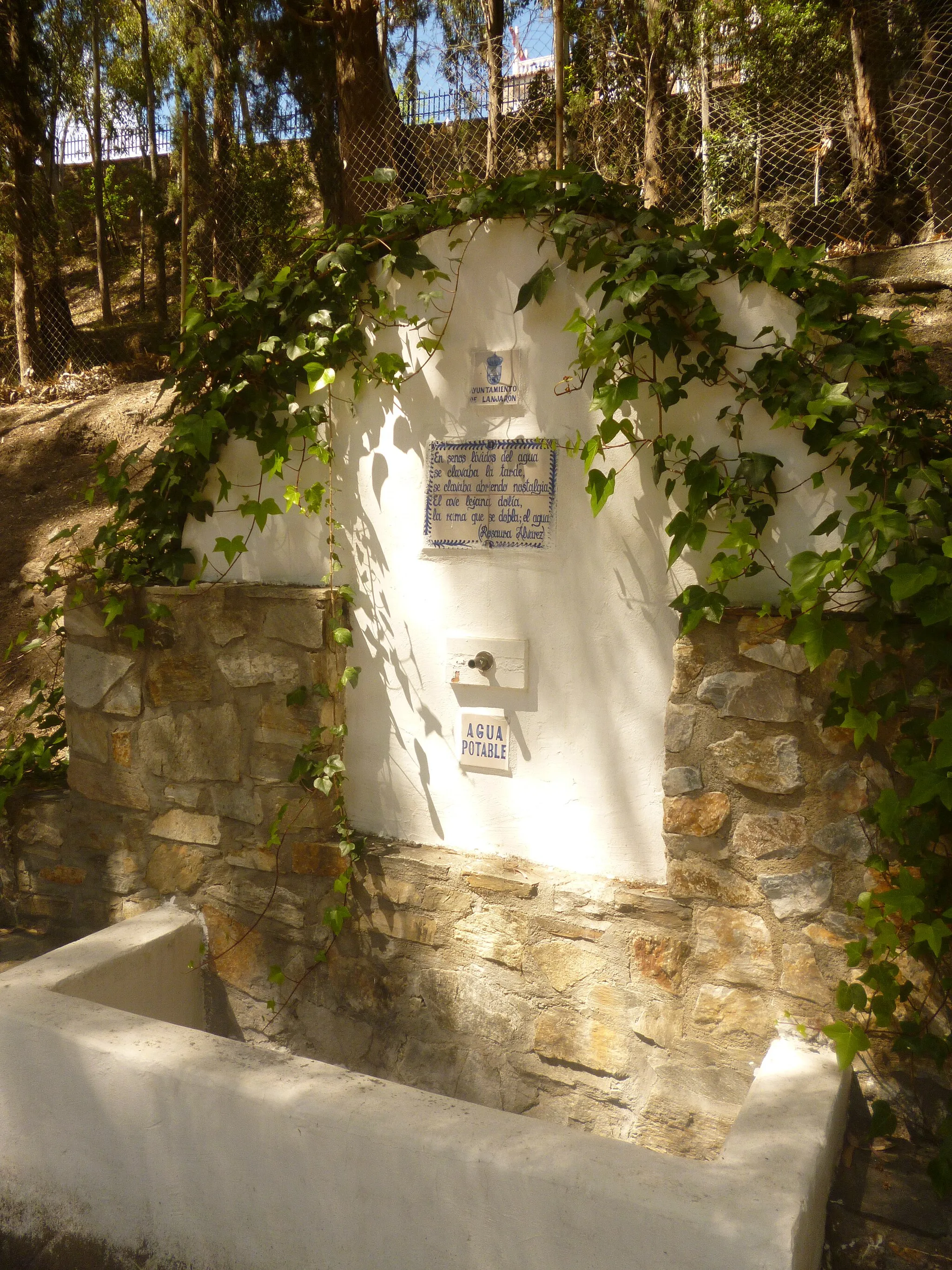 Photo showing: Fuente de agua en el parque El Salado, Lanjarón.
Texto en la fuente:
En senos lívidos del agua
se clavaba la tarde,
se clavaba abriendo nostalgia.
El ave lejana dolía,
la rama que se dobla; el agua.

--Rosaura Álvarez