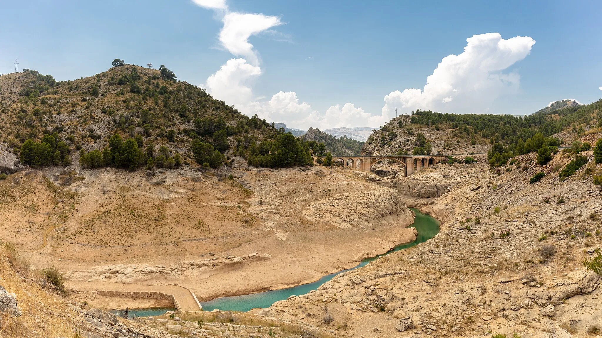 Photo showing: Yeste.—Cauce del río Tus en una de las colas del embalse de Fuensanta, durante un periodo de sequía. Al fondo, un puente de la carretera CM-3206.