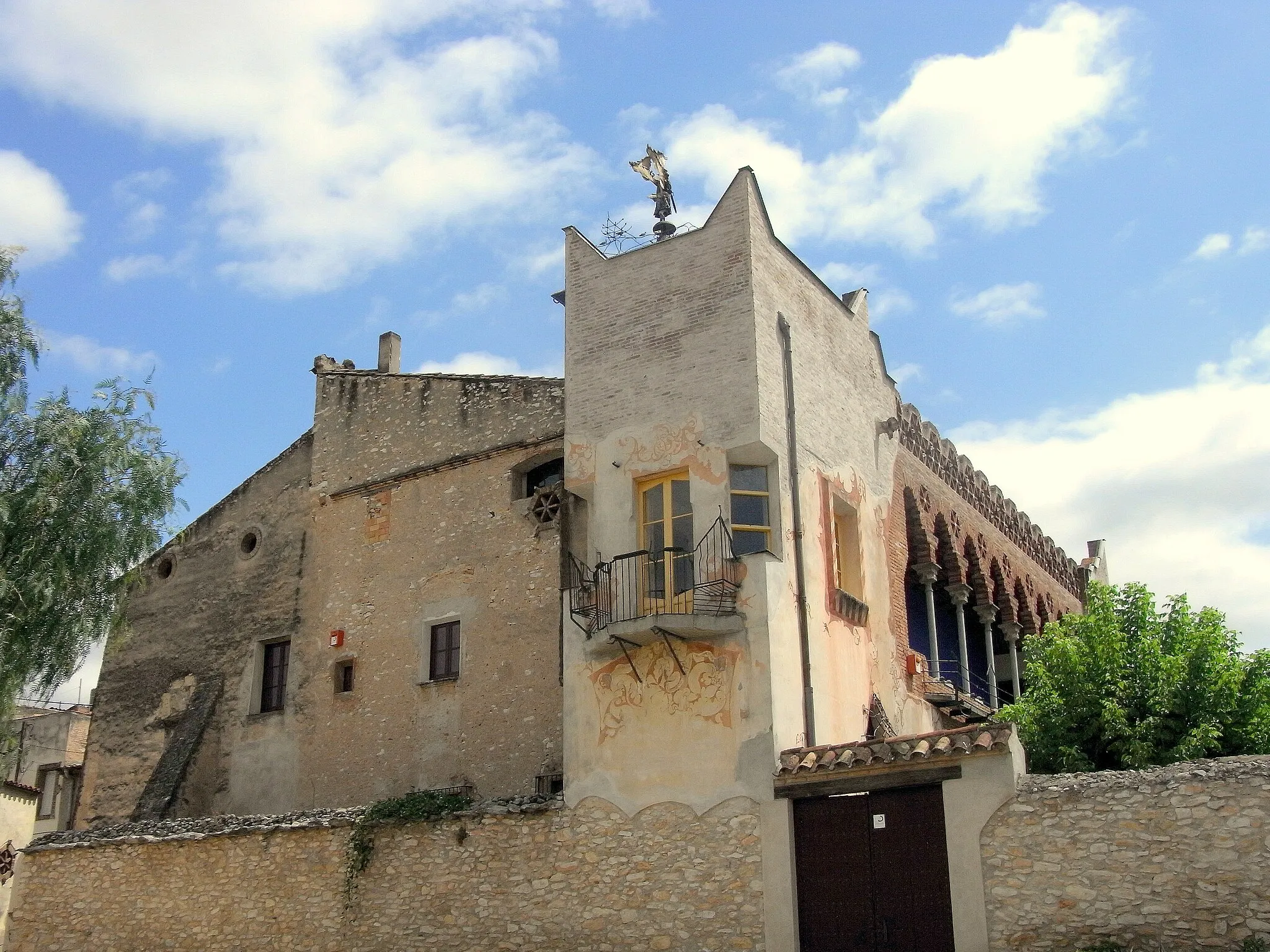 Photo showing: Els PALLARESOS - Casa Bofarull, de Josep M. Jujol.
Josep M. Jujol (1879-1949) ha deixat bon testimoni de la seva genialitat en el poble dels Pallaresos. D´entre les nombroses obres que hi va dur a terme en sobresurt la Casa Bofarull, la construcció de tipus civil més representativa  d´aquest gran arquitecte a les comarques tarragonines. L´actuació de Jujol en aquest edifici rural, duta a terme entre els anys 1914 i 1931, respon a l´objectiu d´eliminar-ne l´aspecte descurat que presentava i ennoblir-lo.
A la façana principal de la casa, orientada a l´oest, hi destaca la porta d´accés amb uns arcs semicirculars d´estil romànic; en el centre de l´arquivolta més exterior hi apareix l´inscripció "Ave Maria" en lletres modernistes. L´obertura al seu damunt és de característiques molt peculiars. L´eix central i més destacat, però, de la Casa Bofarull és l´escala-torre de planta quadrada. Aquest cos és coronat per una peculiar teulada de ceràmica de quatre vessants damunt de la qual s´aixeca un àngel parallamps dissenyat en principi com a penell. Més a ponent, en un angle, s´alça una torre, coronada per uns merlets piramidals cantoners, en la qual s´obren uns balcons amb fantasioses baranes metàl-liques reforçades i unes finestres aixamfranades encaixades en les seves arestes. Les obertures d´aquestes finestres presenten uns interessants esgrafiats que s´estenen a altres punts del parament.
A la façana posterior de la casa Jujol va construir una lleugera galeria de maó recolzada en fràgils columnes de fosa. Aquest es pot considerar l´element més historicista del conjunt, ja que recupera les clàssiques galeries de les masies dels segles XVII i XVIII, però amb una clara influència de l´arquitectura islàmica.

Jujol va pintar per a aquesta casa unes pintures al-legòriques de les estacions de l´any que encara es conserven. Una altra de les meravelles de la casa és la reixa que protegeix l´onertura triangular de la paret del jardí, feta amb eines velles de la feina de pagès. Com aquest, la casa Bofarull conserva molts element arquitectònics d´admirable execucuó -reixes, vidrieres, baranes, portes, paviments, esgrafiats o mobiliari- que situen a Jujol en el cim de la creació arquitectònica modernista a Catalunya.