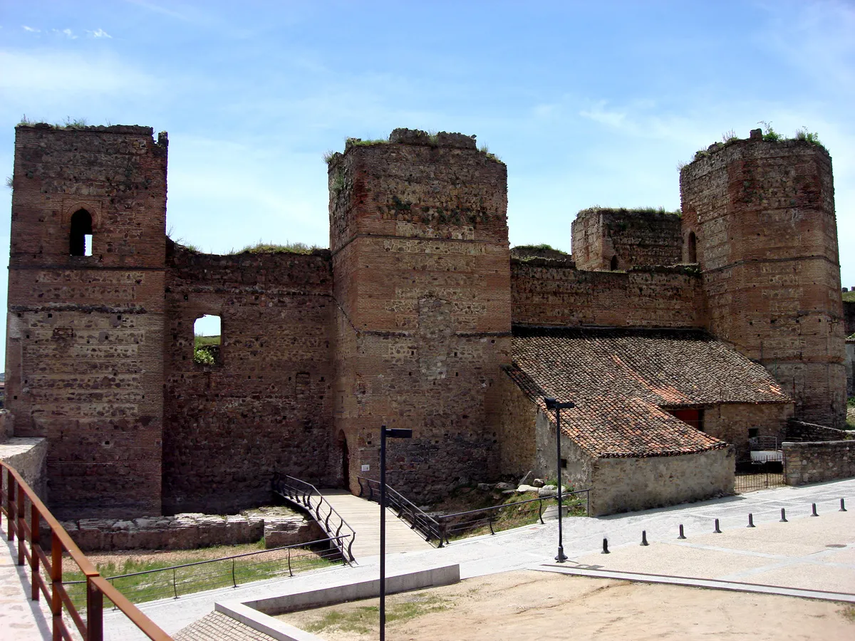 Photo showing: El castillo de Buitrago del Lozoya es un conjunto arquitectónico gótico-mudéjar del siglo XV con planta rectangular, siete torres y un patio de armas central. Este recinto está enmarcado dentro de la muralla, en su esquina sureste, y cuenta con un foso que lo protegía de las invasiones. Las torres son todas diferentes entre sí, habiendo sólo una de planta pentagonal. El acceso se realiza por una puerta en forma de recodo que se sitúa bajo una de las torres.