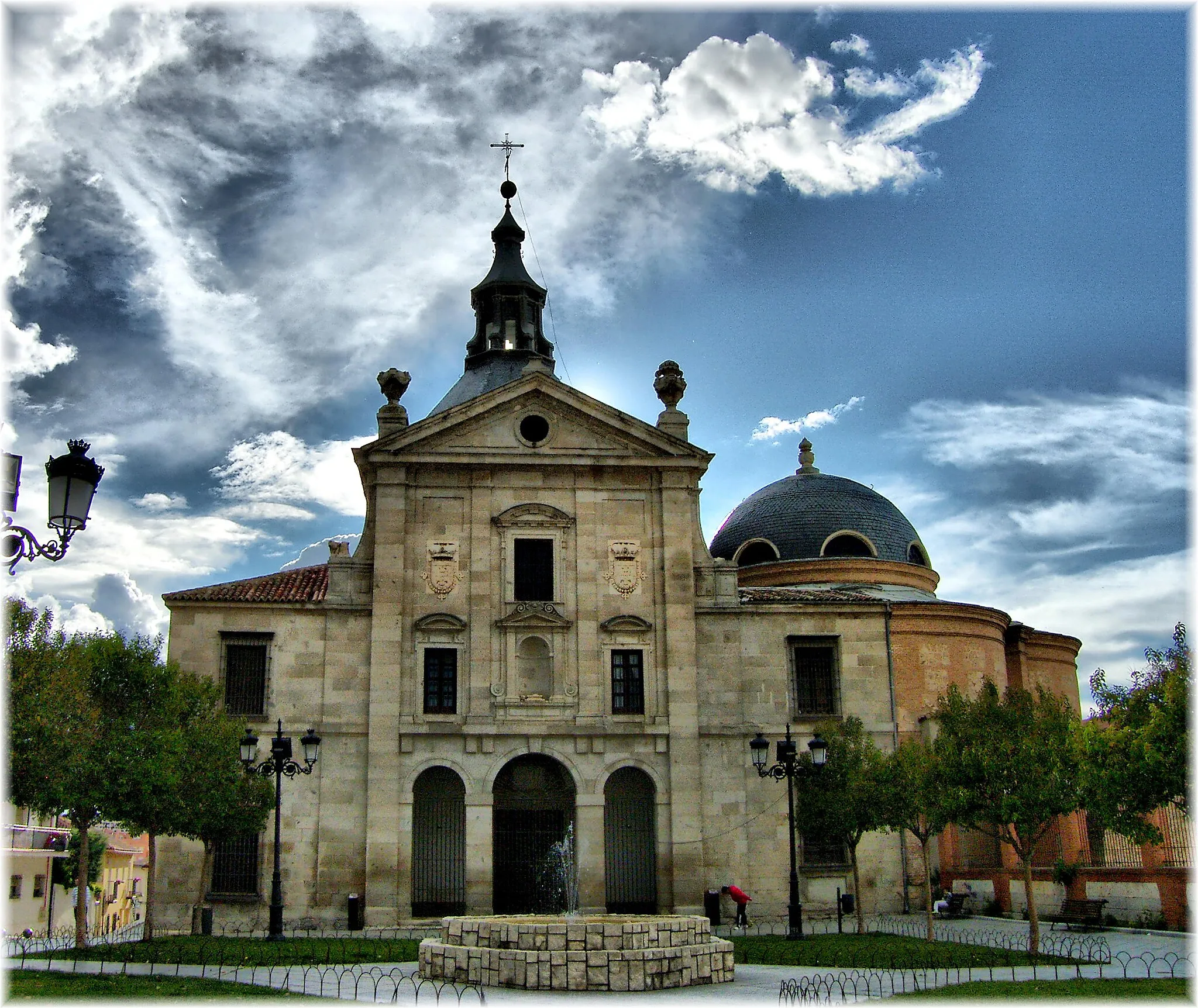 Photo showing: Loeches es una población de Madrid en España. Según el INE, el 1 de enero de 2009 contaba con 6.781 habitantes. Pertenece al partido judicial de Arganda del Rey. Se encuentra al Este de la provincia, entre Alcalá de Henares y Arganda del Rey, en la subcomarca natural de la Alcarria de Alcalá.
Existen datos de ella desde el siglo XII, y su nombre es, según Madoz, de origen vasco, debido a los efectos de la repoblación con pastores vascones durante la reconquista.
Recibió el título de villa en 1555, por parte del Emperador Carlos I de España y V de Alemania.
Felipe II la vendió, junto a otras villas pertenecientes al Arzobispado de Toledo, para sufragar los gastos del Estado con bula del Papa, y el comprador fue el Genovés Baltasar Catanno. Este a su vez vendió el señorío a la familia Cárdenas-Avellaneda.
La familia Cárdenas fundó allí el Convento de carmelitas de San Ignacio Mártir en 1596, y allí permanecen inhumados
El Conde-duque de Olivares compró el señorío en 1633. Pretendió hacerse con el patronazgo del monasterio de carmelitas pero no lo consiguió. Por ello encargó a Alonso Carbonel (arquitecto del Buen Retiro), la obra de un nuevo monasterio, el Monasterio de la Inmaculada Concepción, frente al anterior, muy similar al Real de la Encarnación de Madrid.
En 1643 el Conde-duque de Olivares cesó como primer ministro de Felipe IV y fue desterrado a Loeches, proyectando convertir sus montes en un gran coto de caza, pero la oposición de los agricultores se lo impidieron. En 1645, el Conde-duque dejó Loeches al ser desterrado a Toro (Zamora) pues sus enemigos querían alejarlo aún más de la corte. Ese verano murió y fue llevado nuevamente al monasterio de Loeches donde permanece enterrado hoy día.

Wikipedia