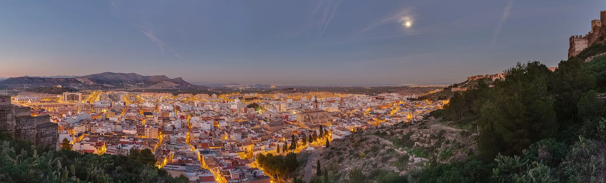Photo showing: View of the former roman city of Sagunto, Valencian Community, Spain, after sunset at the moon light from the hill where the castle is located.