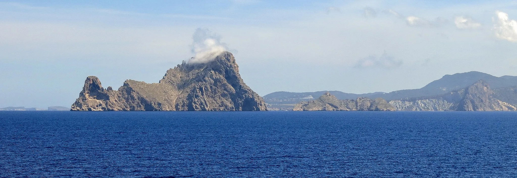 Photo showing: Es Vedrà és un illot que es troba a 2 km de la costa occidental d'Eivissa, davant de Cala d'Hort. Pertany al municipi de Sant Josep de sa Talaia i no està habitat. Té una altitud de 382 m, i al seu costat es troba Es Vedranell, de 128 m. Els dos illots, juntament amb els illots de Ponent (les illes Bledes, l'illa de s'Espartar, l'illa des Bosc i l'illa de sa Conillera), formen part de les Reserves naturals des Vedrà, es Vedranell i els illots de Ponent), protegides pel Decret 24/2002 des de l'any 2002. (Viquipèdia)