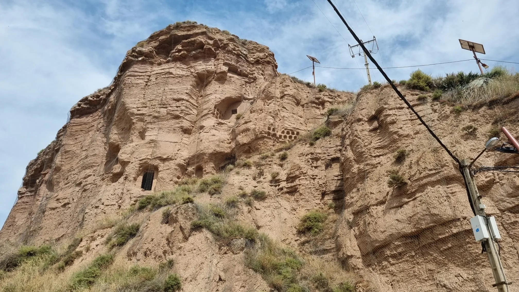 Photo showing: Lo que queda del Monasterio de San Martín de Albelda. El único habitáculo que se conserva y se usa es la ermita de La Panera, la unica que se mantiene en pie y mantiene el culto. En este monasterio se creó la crónica Albeldense. Se pueden observar los agujeros que recubrían el interior de las distintas estancias, típico en otraa cuevas eremitas de la misma zona.