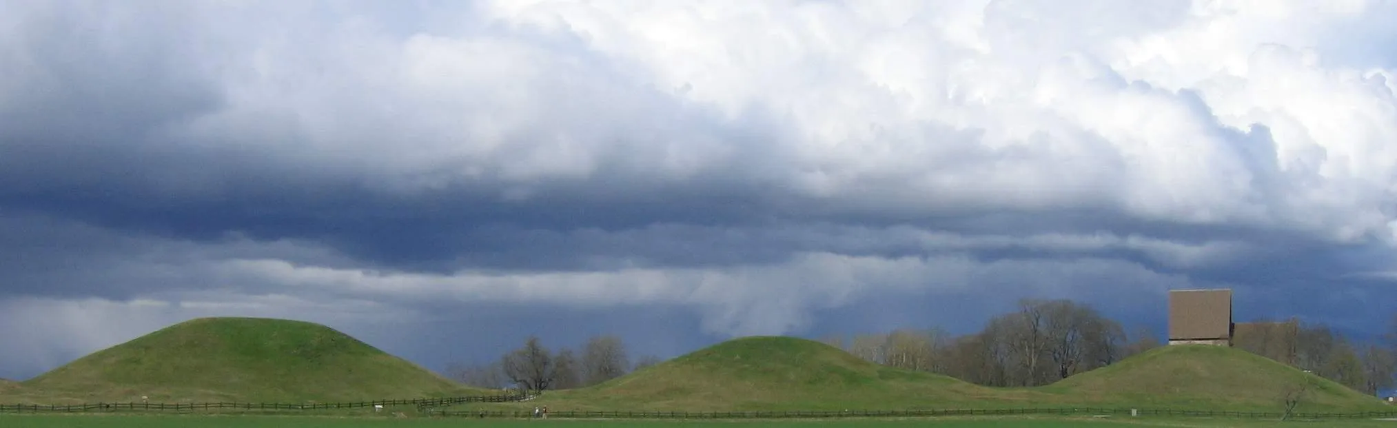 Photo showing: The three large "royal mounds" at Gamla Uppsala, Sweden. In the background to the right one can see part of Gamla Uppsala church, built in the mid 12th century.