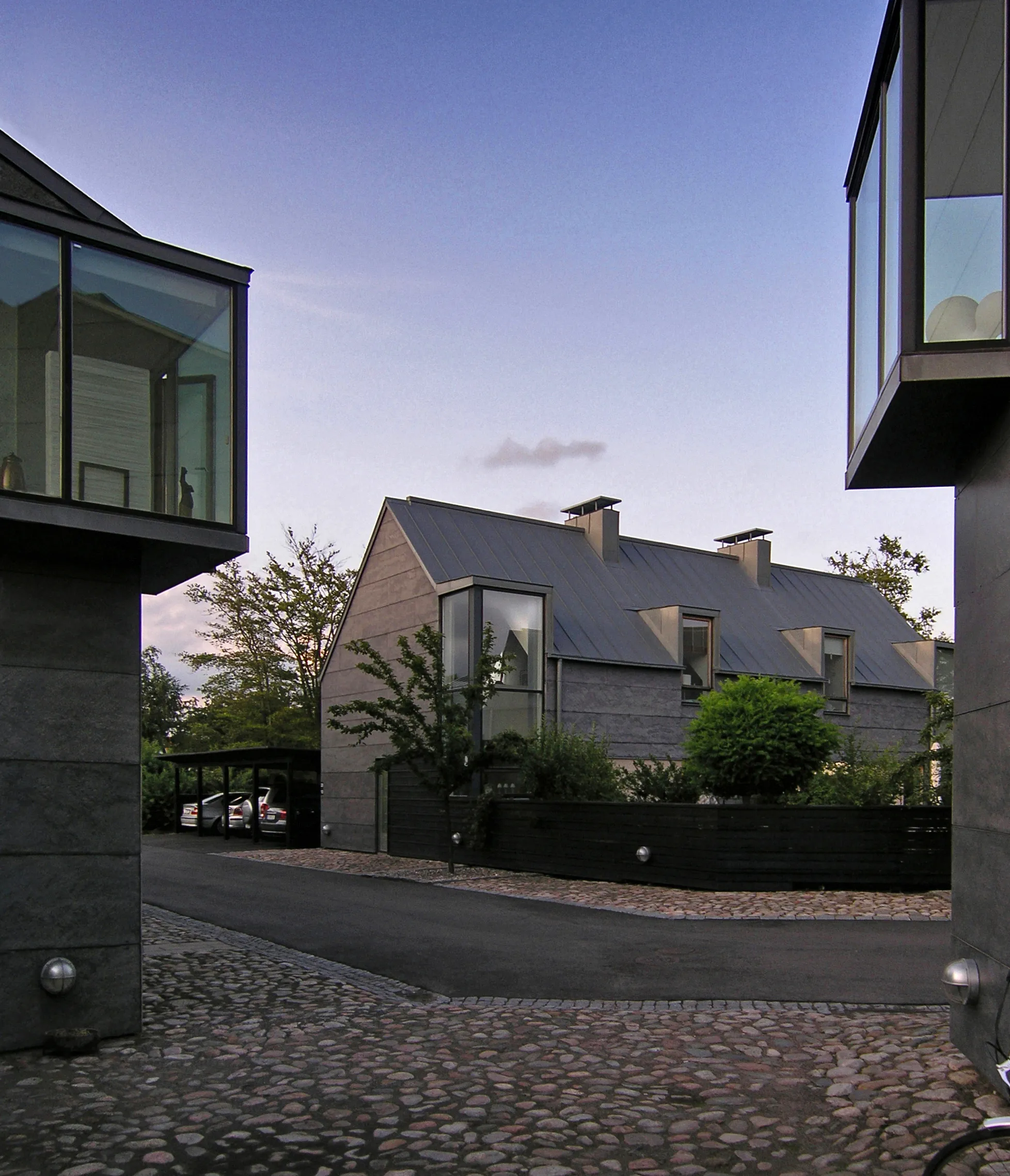 Photo showing: tre gudor housing, viken, sweden (2000)
architects: tegnestuen vandkunsten
this rather fine project by flemming ibsen and jens thomas arnfred came long after vandkunsten had given up their political agenda but still displays lessons from the early works on the question of scale and not least on the social space in housing, here best illustrated by the old office truism that once the architects are done, it is easier to put in an extra curtain than an extra window. we must challenge people's privacy, once it has been established, there is no going back.
the corner windows do allow neighbours to look into your home, but only a limited area which people typically use to show who they are. a challenge for the somewhat buttoned-up swedes, no doubt.

they also, and this is very much part of their attraction, bring the werkbund-like houses into the 21st century when lit from the inside at night.