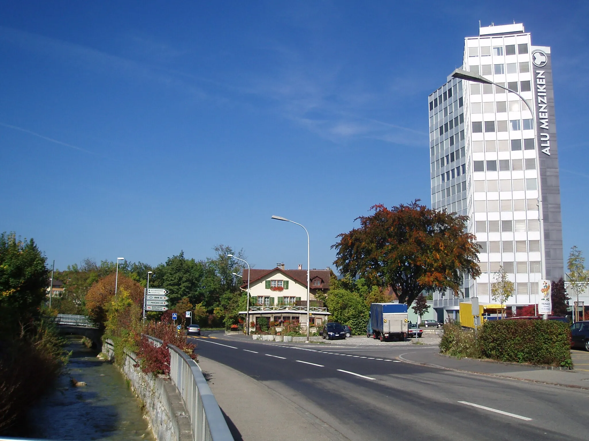 Photo showing: From left to right:

River Wyna
Main street
"Aluminium Hochhaus", the tallest building of Menziken, Switzerland (headquarter of Alu Menziken Gruppe)