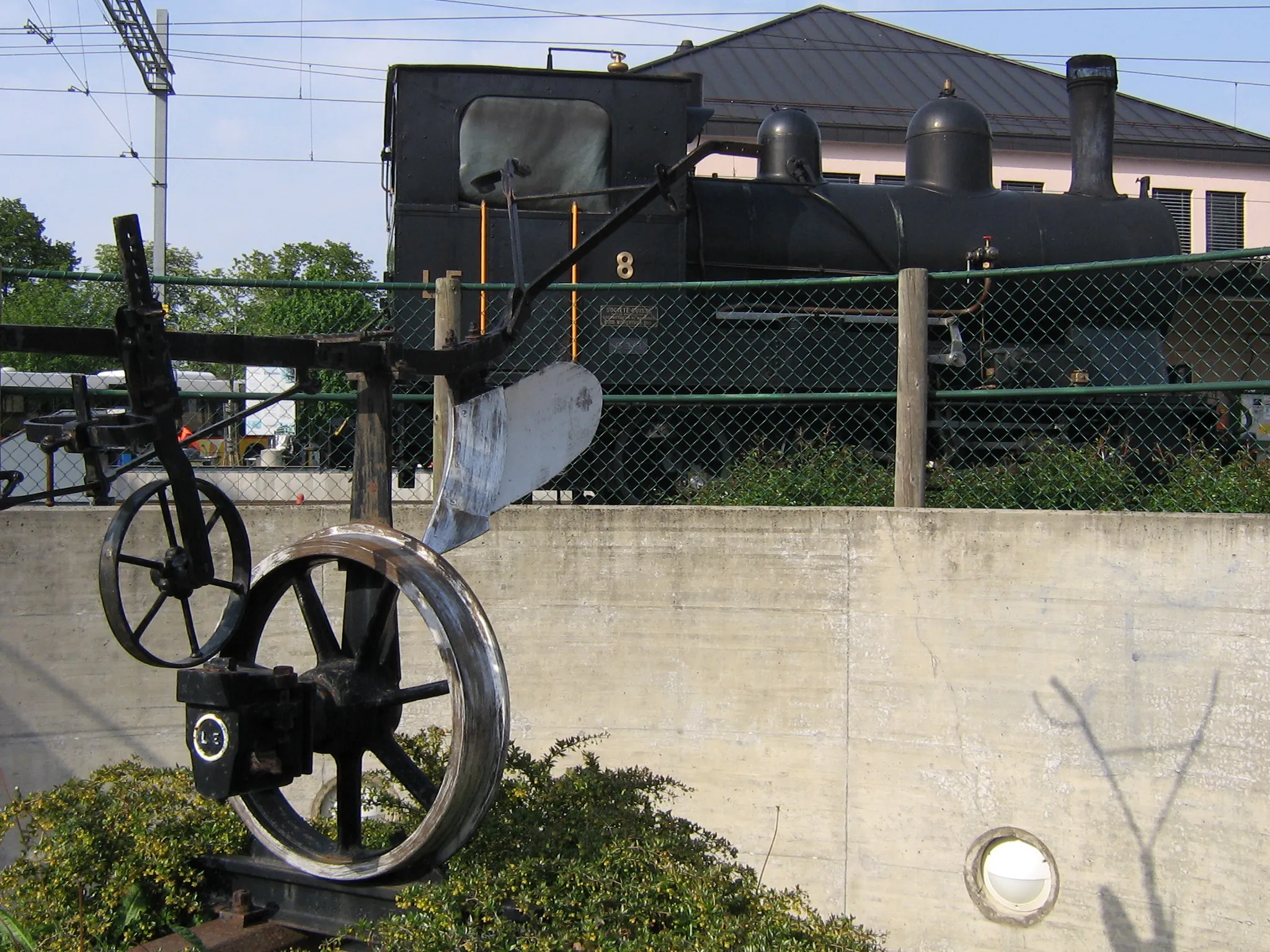 Photo showing: In the background, locomotive G 3/3 8 Echallens at Echallens workshop. In the foreground, a sculpture made from old railway equipment.