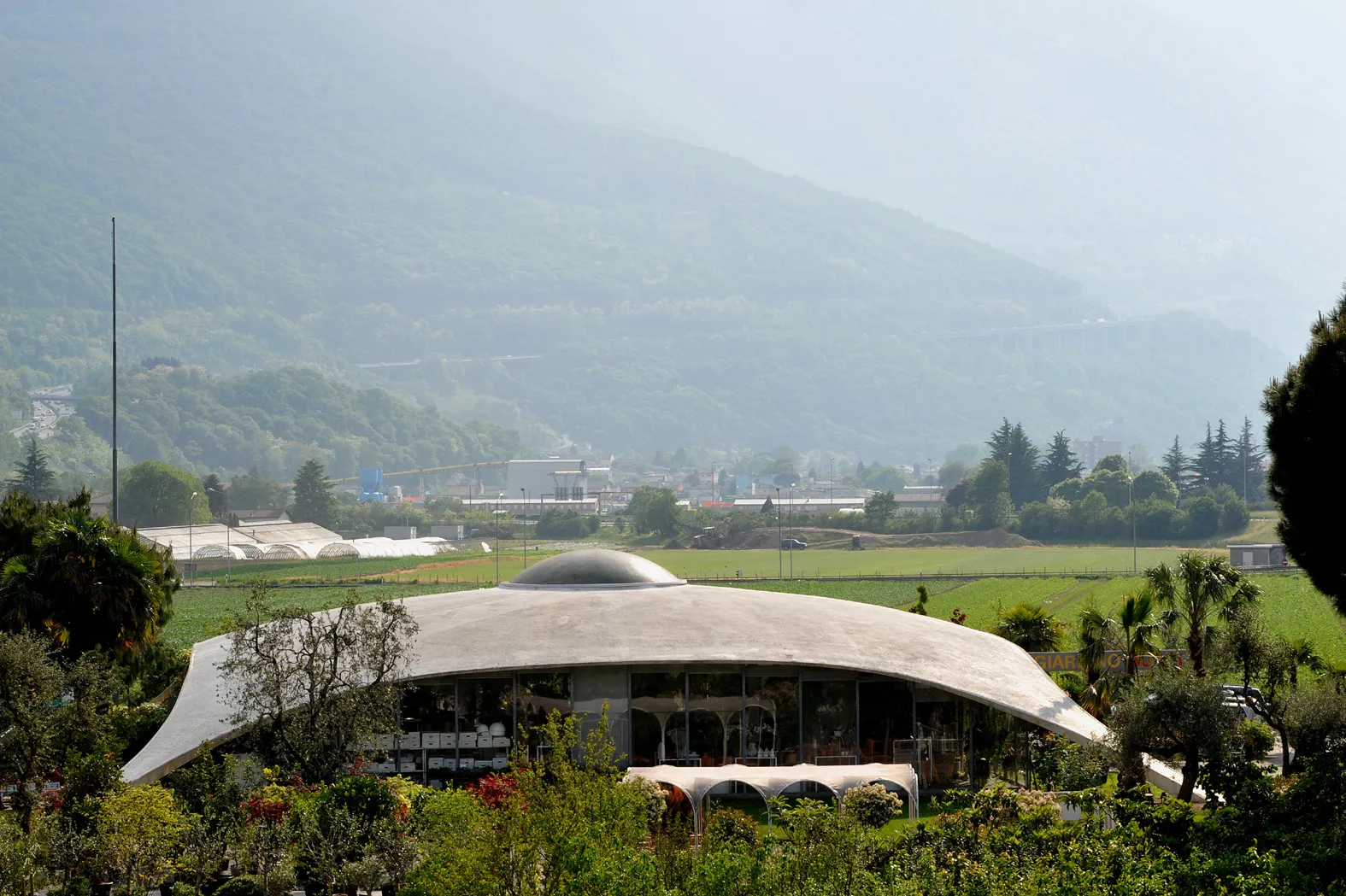 Photo showing: Concrete shell roof (Isler shell) of the Garden Center Bürgi in Camorino, built 1973; Ticino, Switzerland.
In the background the road to the Monte Ceneri Pass.
