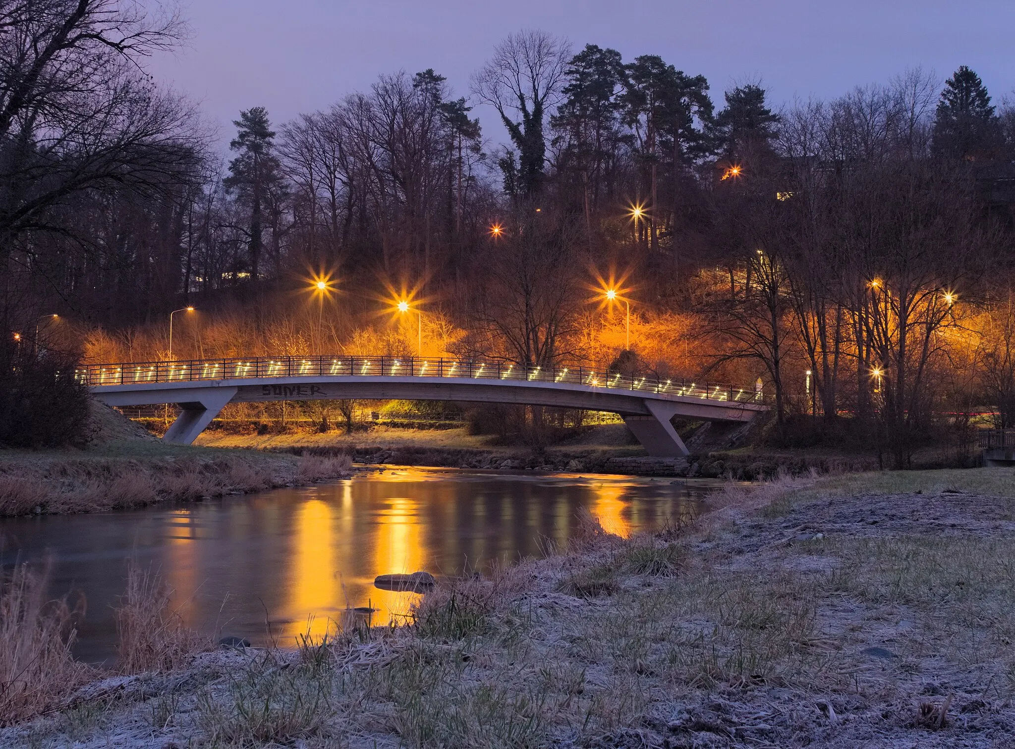 Photo showing: The Werdsteg is a foot and bicycle bridge crossing the Sihl river in Adliswil.  The picture shows it with lights still on during dawn.