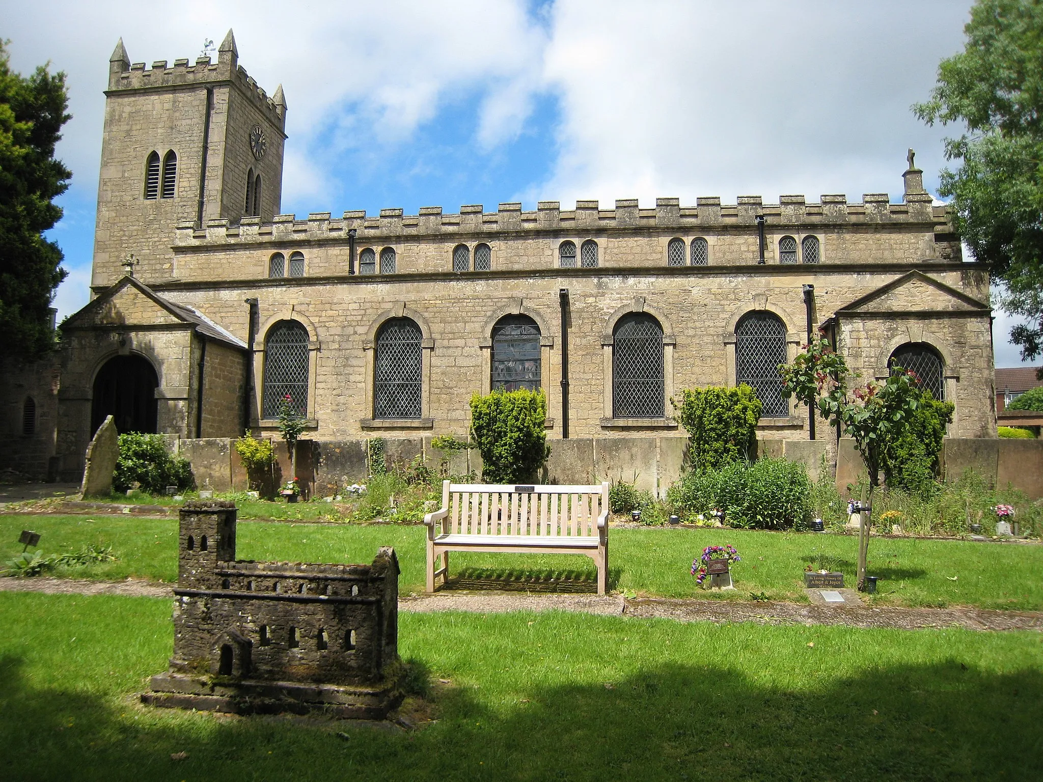 Photo showing: Church of St Mary of the Purification, Blidworth.  View from the South, the graveyard, showing the East clock face.  In the foreground is a model of the church in earlier times, made in 1963.  Grade II* listed building.