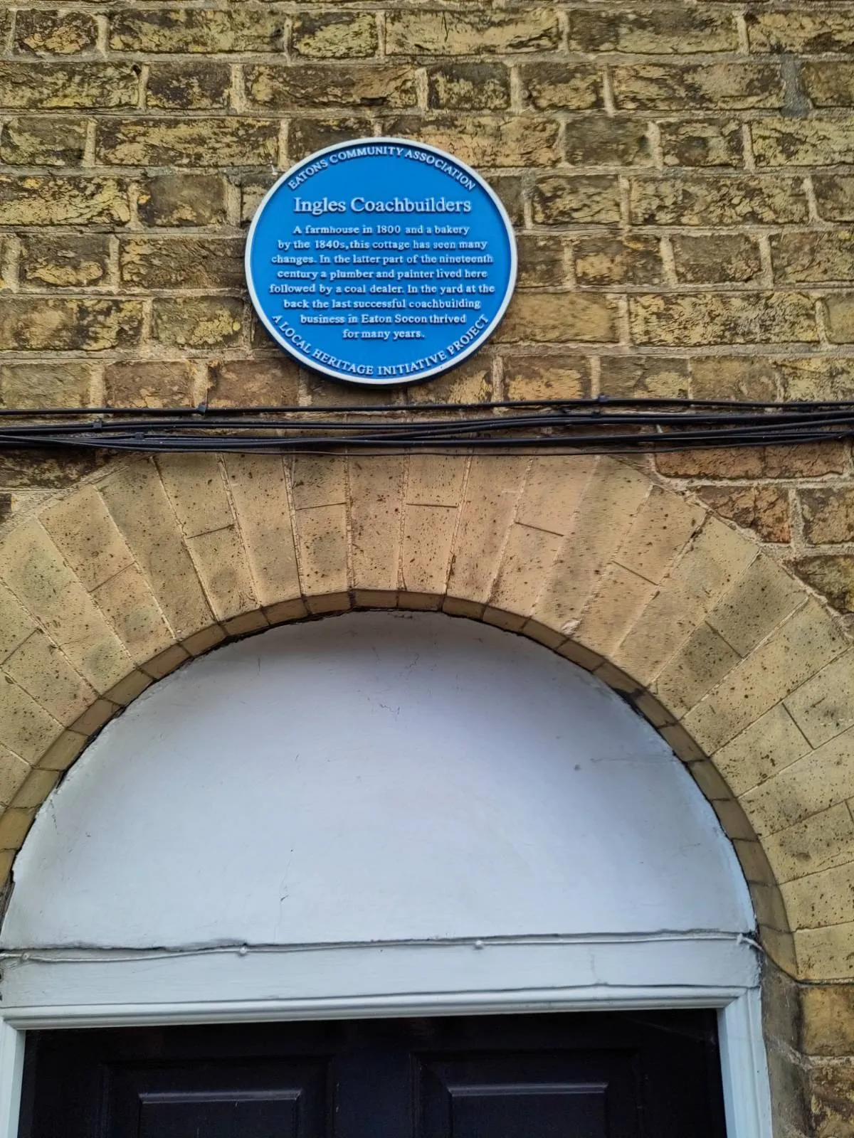 Photo showing: Plaque for former Ingles Coachbuilders on 200 Great North Road, Eaton Socon, St Neots. It reads "Ingles Coachbuilders A farmhouse in 1800 and a bakery by the 1840s, this cottage has seen many changes. In the latter part of the nineteenth century a plumber and painter lived here followed by a coal dealer. In the yard at the back the last successful coachbuilding business in Eaton Socon thrived for many years."