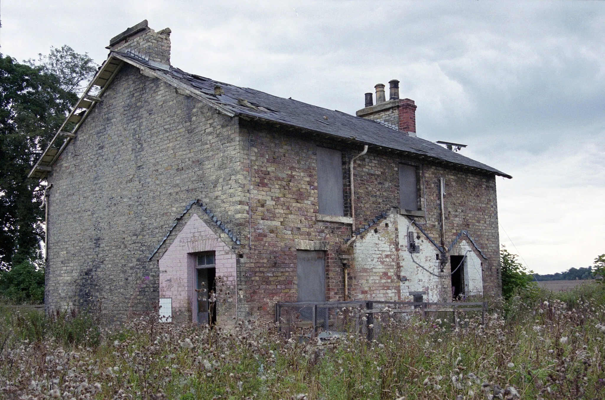 Photo showing: A photographic film image of a dilapidated and overgrown estate farm worker's cottage taken in 1999, at the east of the Sandhall Park estate, south of Skelton in the civil parish of Kilpin, part of the East Riding of Yorkshire, England. The house, occupied before the First World War by the family of an estate garthman (yardman and herdsman), had its own family garden, livestock pens and outbuildings and extensions. A decrepit chicken coop is against the back of the house. Although the house from the one front door appears single occupancy, the back and sides indicates a possible split into two living units. Processing: SLR camera negative scanned with an Epson Perfection V800 scanner and optimized and cropped and spun with Adobe Photoshop CS2.