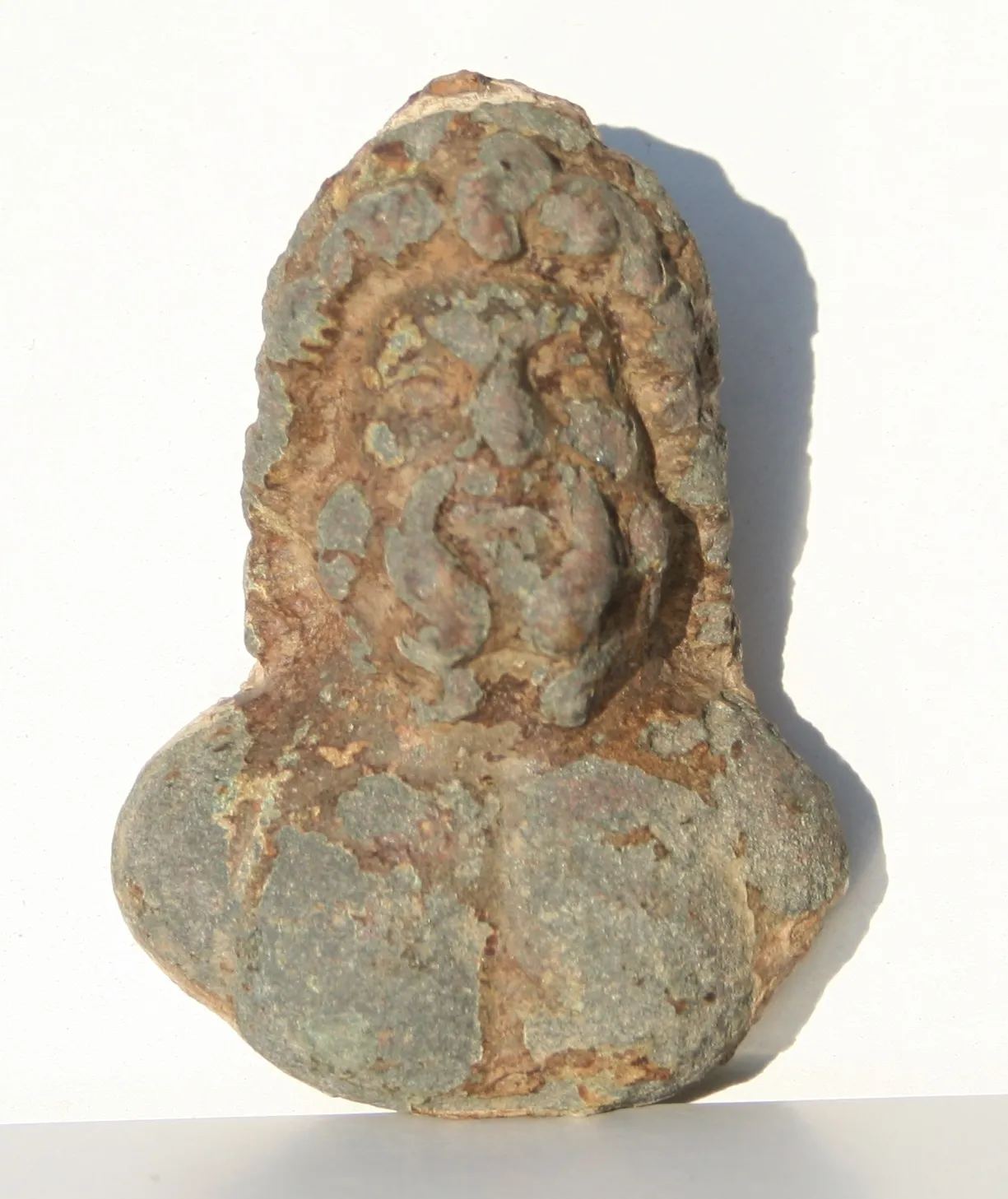 Photo showing: A cast, copper alloy bust of probable Roman date. The object depicts a male bust and measures 75.90mm in length, 54.06mm at the widest point, 32.86mm in thickness. It weighs 365g. The bust has a green patina, with traces of iron at the top of the head and on the back of the mount with possible traces of lead or solder.