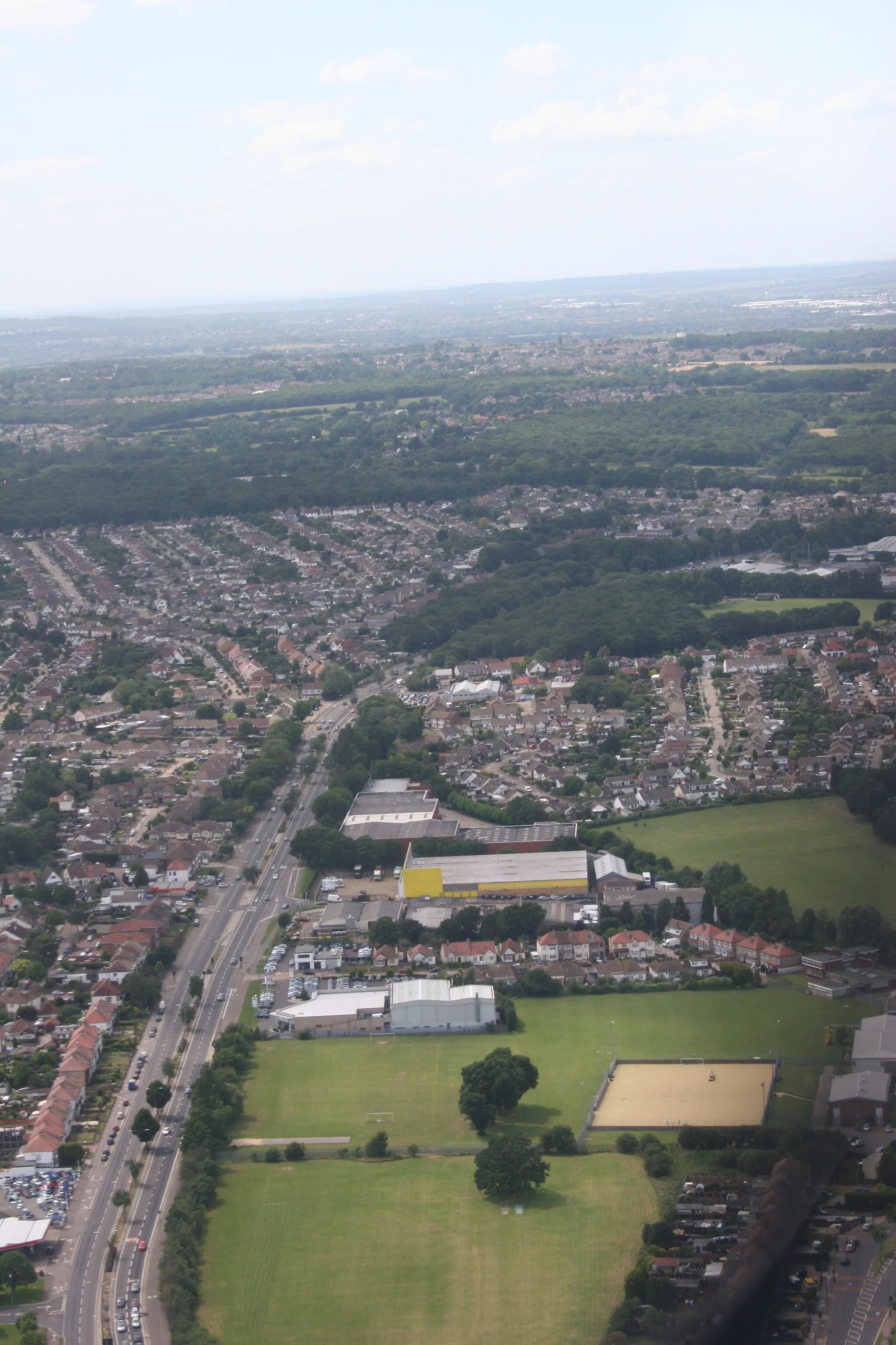 Photo showing: A127 between Rayleigh Road (A1015) Kent Elms Corner and almost to Progress road. Kent Elms is off-camera below. The A127 cuts through a circular wood (Oakwood Park) as it curves right. Immediately beyond Oakwood Park is Progress Road: the junction with the A127 is just visible among trees. Places shown are Belfairs (left) and Eastwood (right).