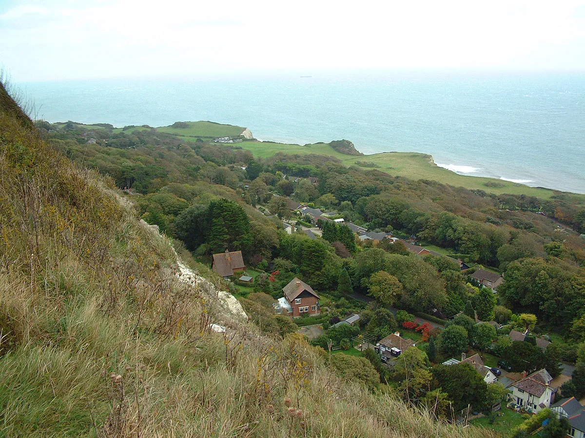 Photo showing: Isle of Wight Undercliff at St. Lawrence, view from Isle of Wight Coastal Path. The Undercliff is a south-facing tract of land, backed by cliffs and formed by landslip processes in Cretaceous rocks, whose sheltered location provides a unusually mild microclimate. It is the location of the Ventnor Botanical Garden, which is on the site of the now-demolished Royal National Hospital for Diseases of the Chest, a tuberculosis sanatorium that was established there to exploit the same mild climate.