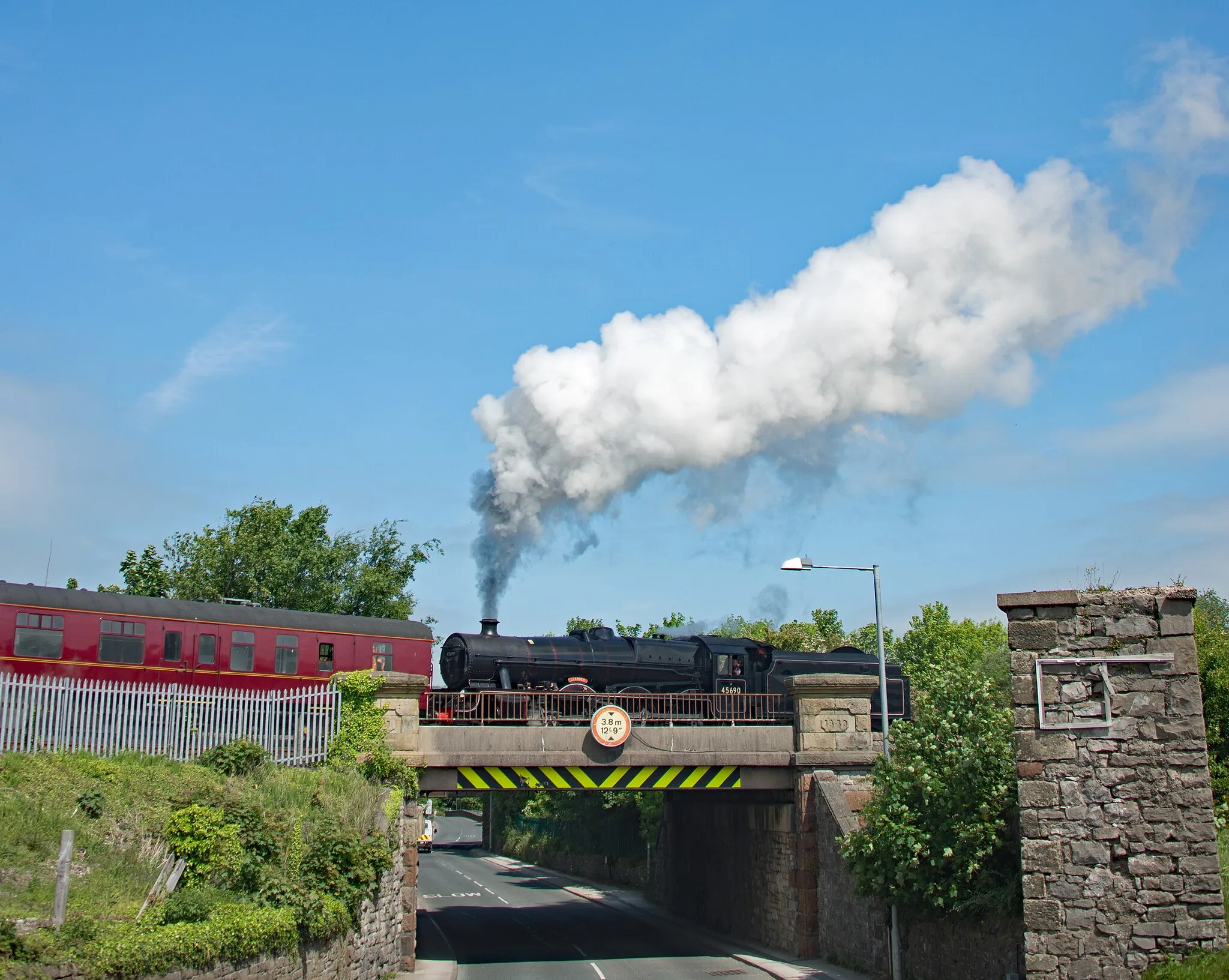 Photo showing: 45690 Leander steaming across the road bridge out of Carnforth on its light test run to Hellifield.