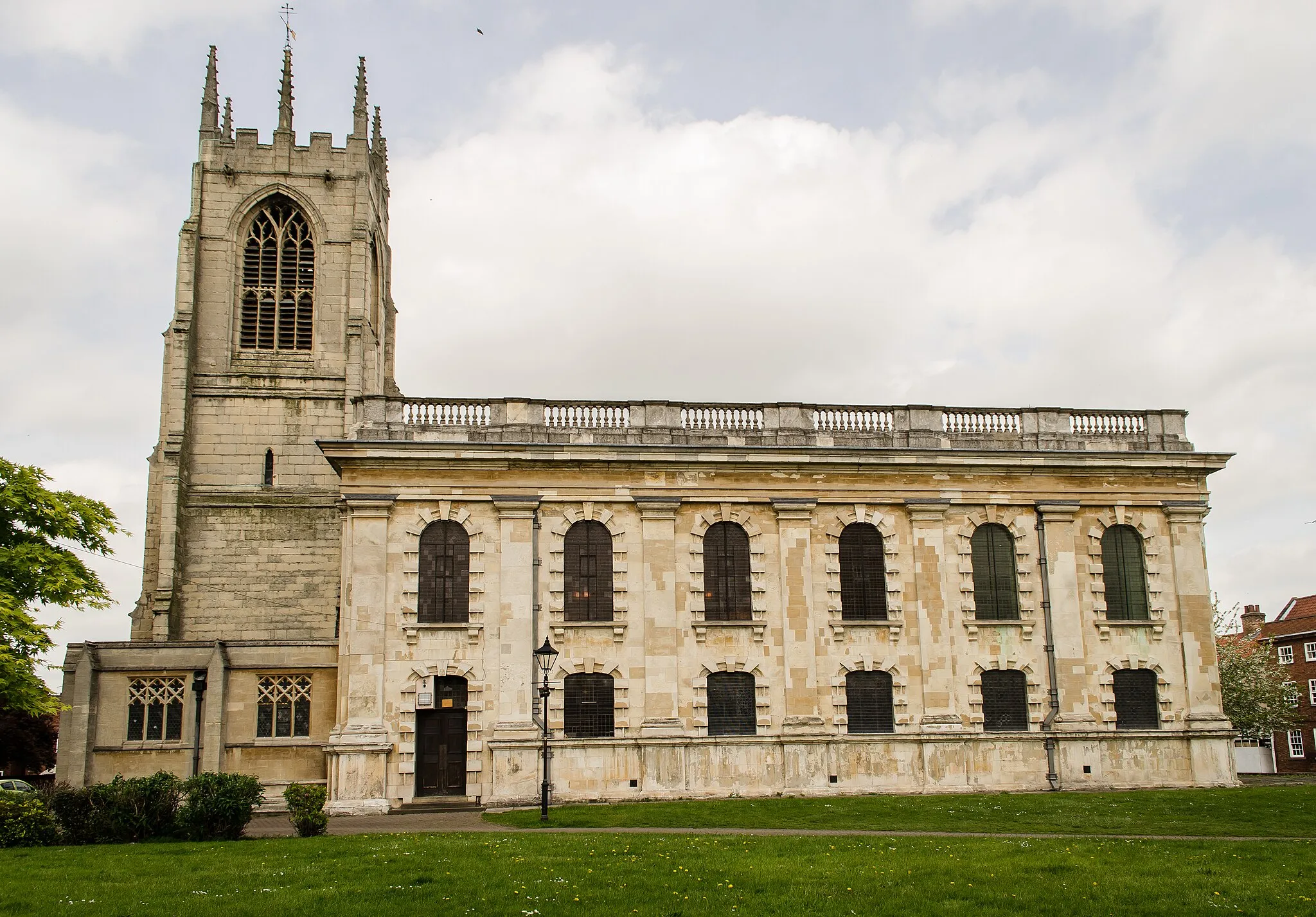 Photo showing: Grade I listed.
The church (except the tower) replaces an earlier mediaeval church.
The earliest mention of the church is in 1185 when it was given to the Knights Templar. It was originally dedicated to the Blessed Virgin Mary and later contained two chantry chapels with tombs of the De Burgh family surmounted by marble effigies. These appear to have been lost when the church was demolished.
The original church had a chancel, nave with aisles and a clerestory, probably from the 14th century.
It was not a handsome building, and in 1734 was in a very poor state, with numerous cracks, rotten timbers and leaning walls. The decision was made to build a new church, large enough to accommodate upwards of 3000 people. They considered the cost to be £3000, this was to be raised by a local tax, which was much opposed.
In 1736 an act of Parliament was obtained to raise the money. In 1740 a second act was procured to raise £1000 more by levying a duty on Coal.
Demolition of the old church began in 1736, and the new church was open, although not complete in 1744.
The architect was Francis Smith (1673-1738).
The tower is the only surviving part of the old church, and was originally surmounted by a spire. This was removed in the 18th century. There are eight bells, most made in the 18th C.
The church was built in the classical style. The nave has six bays and can seat 700. There are box pews and galleries to the north and south walls.
The original windows were plain glass.
To the north is a Lady Chapel containing a window designed by G. F. Bodley. Formerly this was the Thonock Chantry.
The chancel has an apse at the east end with a Venetian window and glass by Wailes. Under the mediaeval Quire Sir Edward Burgh, who first married Catherine Parr was buried in 1533. On the east wall is a copy of the last supper by Leonardo da Vinci, this was painted on dry plaster in 1874.
To the south is Saint Michael's Chapel, which was originally the Burgh Chantry with a Memorial to the Hickman family, who were Lords of the Manor.
The south wall of the nave contains a Morris window designed by Edward Burne-Jones from 1914.
Various restorations occurred over the years, the apse was redecorated in 1876, and in 1888 a new font was installed, but in 1968 the Georgian font was bought back into use and a new baptistery constructed.
The organ is a three manual by Walker from 1906.

At the west end of the church underneath the tower, two vestries were built in 1903, one of which is now a cafe and gift shop.