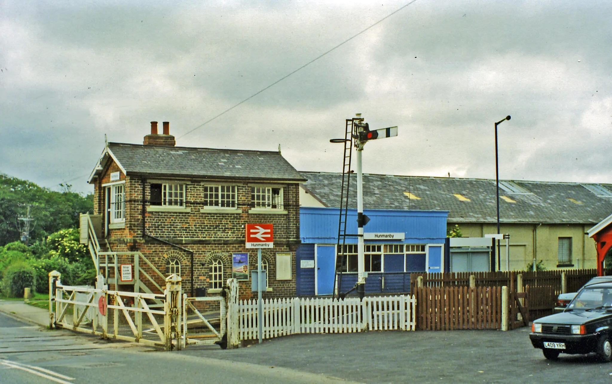 Photo showing: Hunmanby station and level-crossing, 1997.
View westward on the ... road, across the ex-NER (Hull/Leeds etc.) - Bridlington - Scarborough line. The crossing was still controlled by the local signalbox, which is prominent.