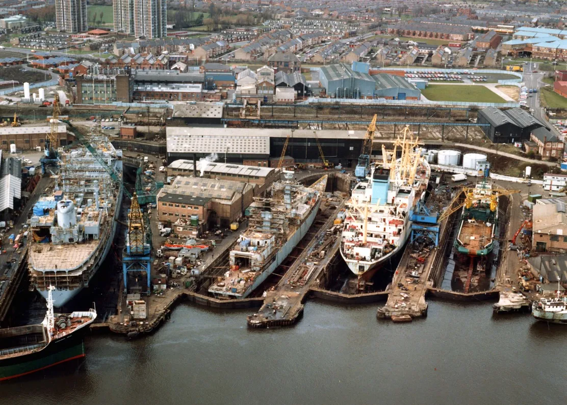 Photo showing: Swan Hunters dry docks, Wallsend 26th March 1987.
From left to right the docks hold a Royal Fleet Auxiliary tanker, a Royal Navy warship, a Nigerian registered cargo vessel and an off shore supply vessel.
Reference Number: TWAS: DS.SWH.5.3.1.12.6
(Copyright) We're happy for you to share this digital image within the spirit of The Commons. Please cite 'Tyne & Wear Archives & Museums' when reusing. Certain restrictions on high quality reproductions and commercial use of the original physical version apply though; if you're unsure please email archives@twmuseums.org.uk.

To purchase a hi-res copy please email archives@twmuseums.org.uk quoting the title and reference number.
