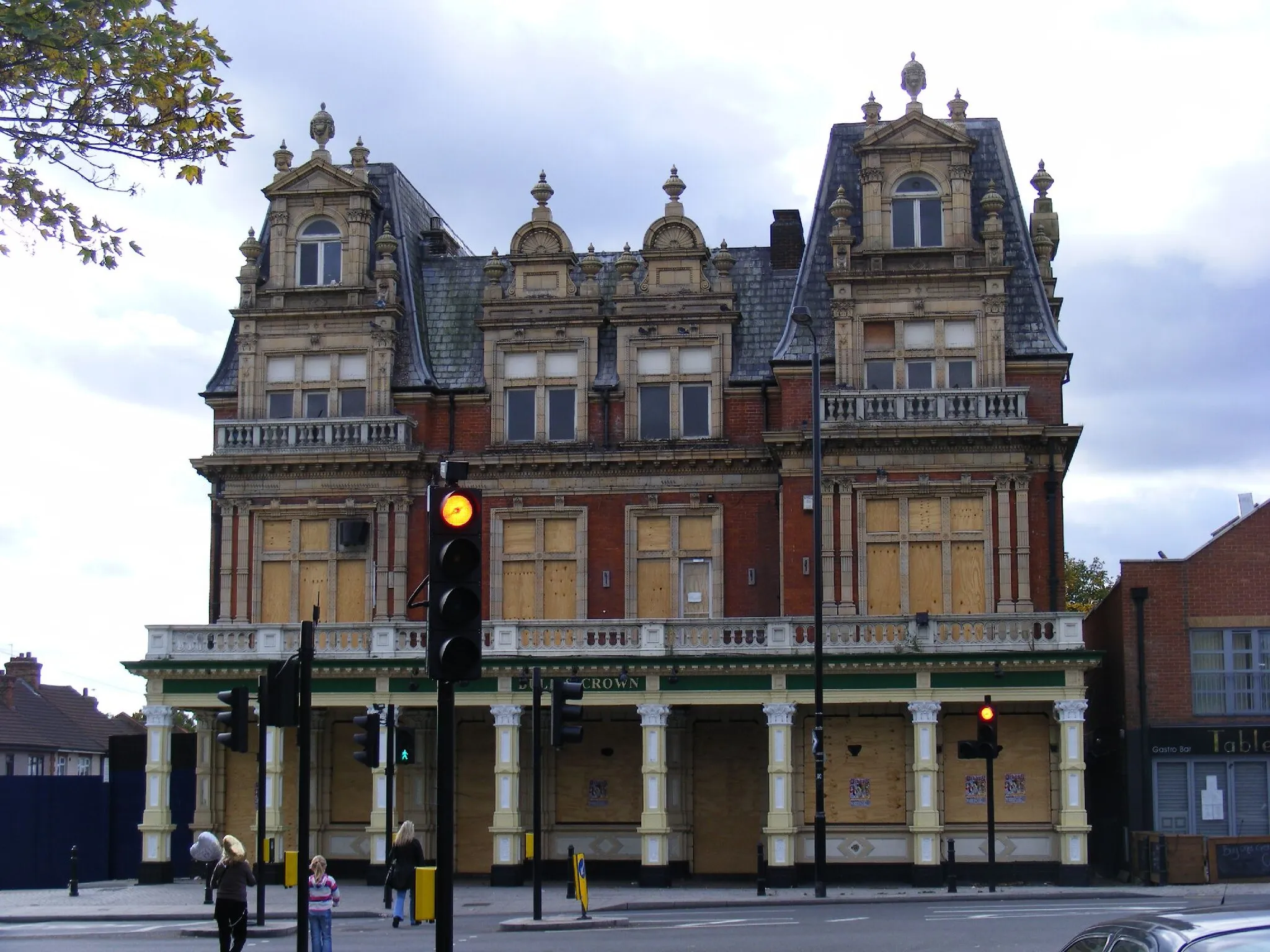 Photo showing: Rather a grand old pub, quite difficult to photograph, hence the stop lights, but I like it in the picture.  I don't know the fate of this building. Apparently the pub was raided by police investigating Drug and Gun crime in July 2009 and has not reopened.  Edwardian with TERRA COTTA  decoration extolled by Pevsner as in" the wildest Loire style"