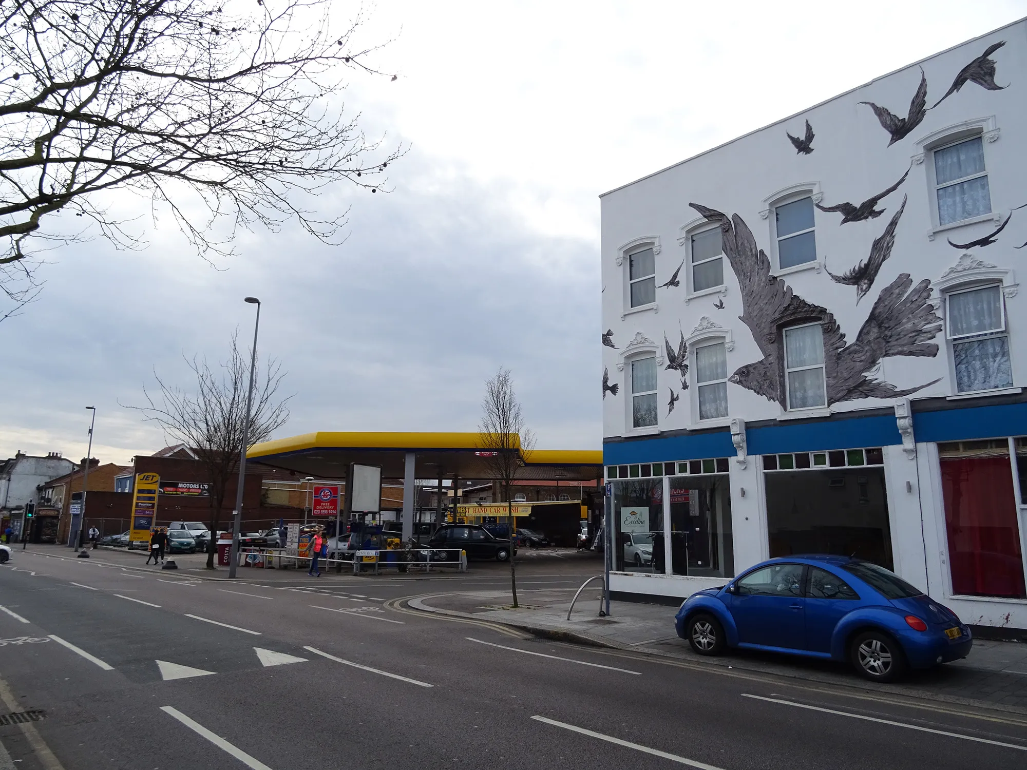 Photo showing: Site of 517 High Road, Leytonstone, London, E11 3EE, birthplace of Alfred Hitchcock. Where the gas station now stands was a row of houses and a grocer's shop, where Hitchcock's family lived and worked, and where, according to several biographers, Hitchcock was born. The houses on the right display a mural from The Birds (1963). In 2014, Mateusz J. Odrobny and Anna Mill painted the mural on the properties running from 527 to 533 High Road.