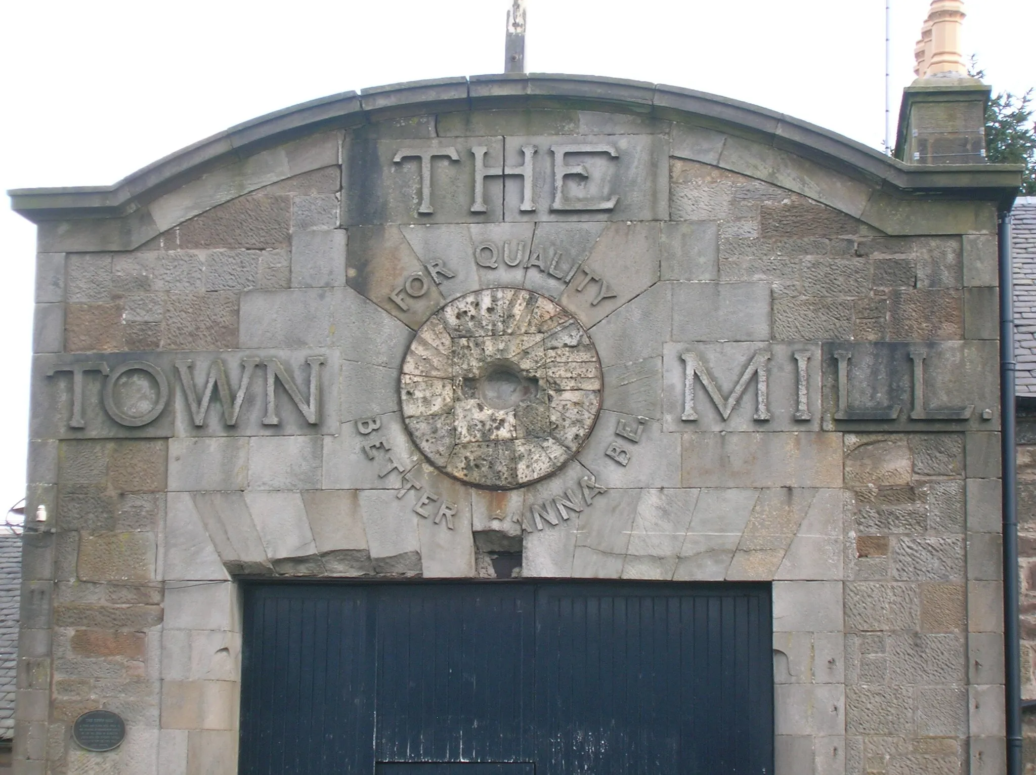 Photo showing: The old Town Mill, Strathaven, South Lanarkshire. Showing details of the stone carving advertisement and old grindstone.