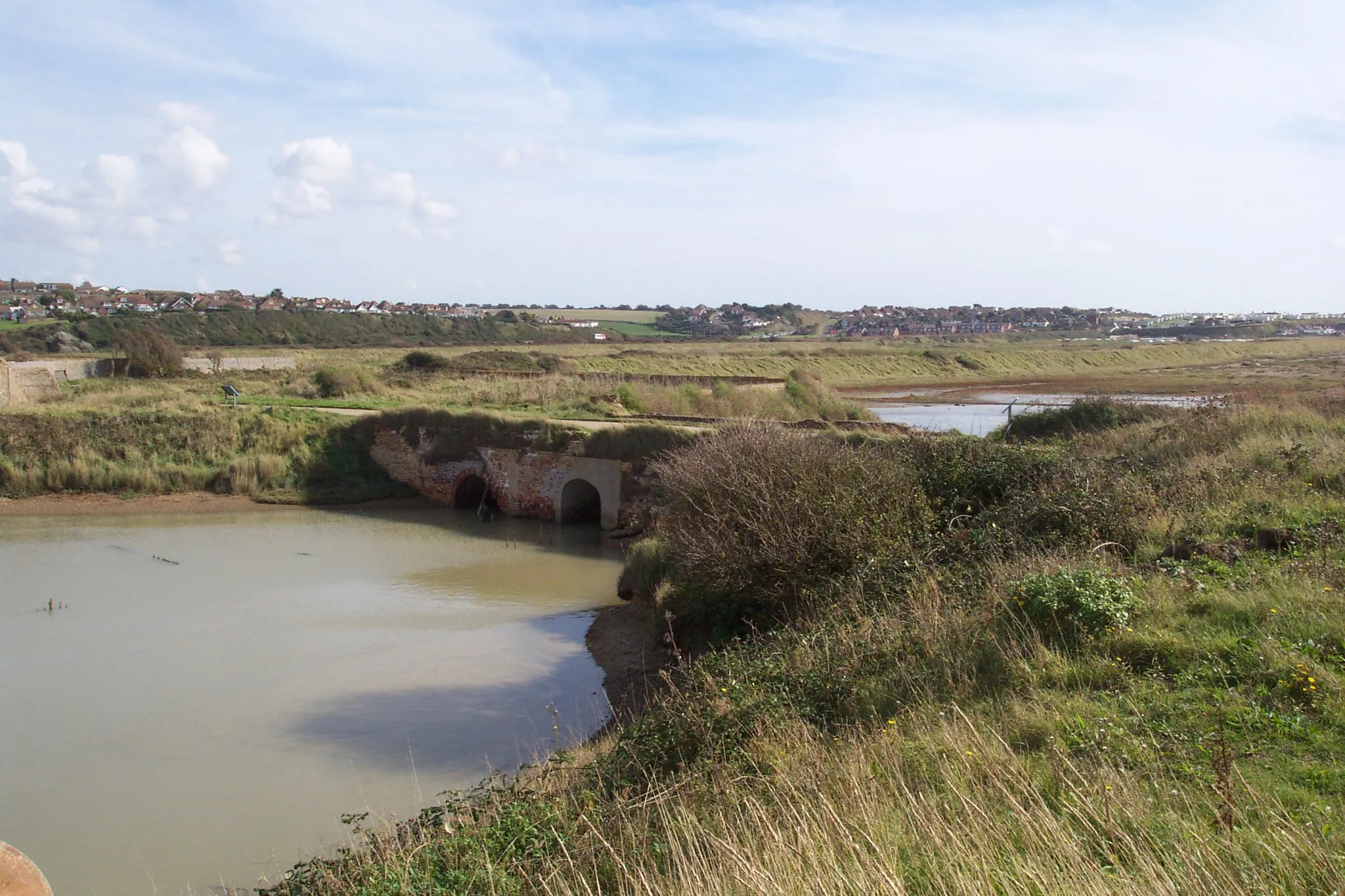 Photo showing: Taken by Tim Trent
Showing the ruins of the en:Tide Mills tidal mill en:sluice from the seaward (riverward) side on a rising tide.  Shown are two arches.  The right hand one connects to the visible opening in en:Image:Remains of Tide Mills mill race sluice - millpond side.jpg