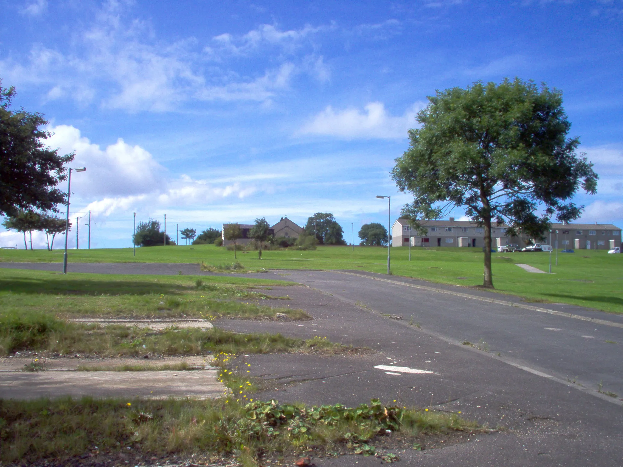 Photo showing: The site of the former Coopers Close Housing Estate, Thornley, Co Durham. One street of Coopers Close houses remains on the site of the former Coopers Terrace prefabs. St Bartholomew's Church can also be seen to the rear. The area in the foreground was a children's recreation ground prior to the building of the estate.