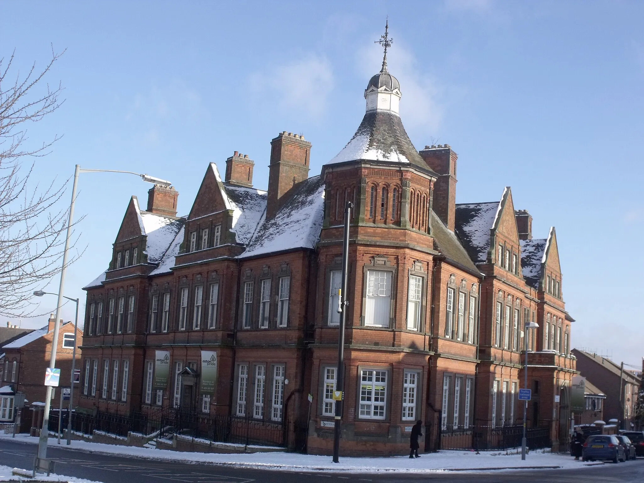 Photo showing: This is Aston Library on the Witton Road in Aston. It was a Free Library that opened in 1882 as the Aston Manor Council Offices and Library.
It is on the corner of Witton Road and Albert Road. The offices of Aston Pride are located within the library.
Aston Pride
Aston Library
It was built for Aston Manor Council in 1882 and was designed by William Henman. It is a two-storey plus attic building of red brick with stone dressings. There is a polygonal corner tower with five bays, each three windows wide, along each street face. The second and fourth bays project and have gables. At the extension of the city boundary in 1911 the building came under the control of Birmingham and it is still used as a library.
(From Victorian Buildings of Birmingham by Roy Thornton).
In Birmingham, Aston Library is locally listed as Grade A.

Birmingham locally listed pdf file