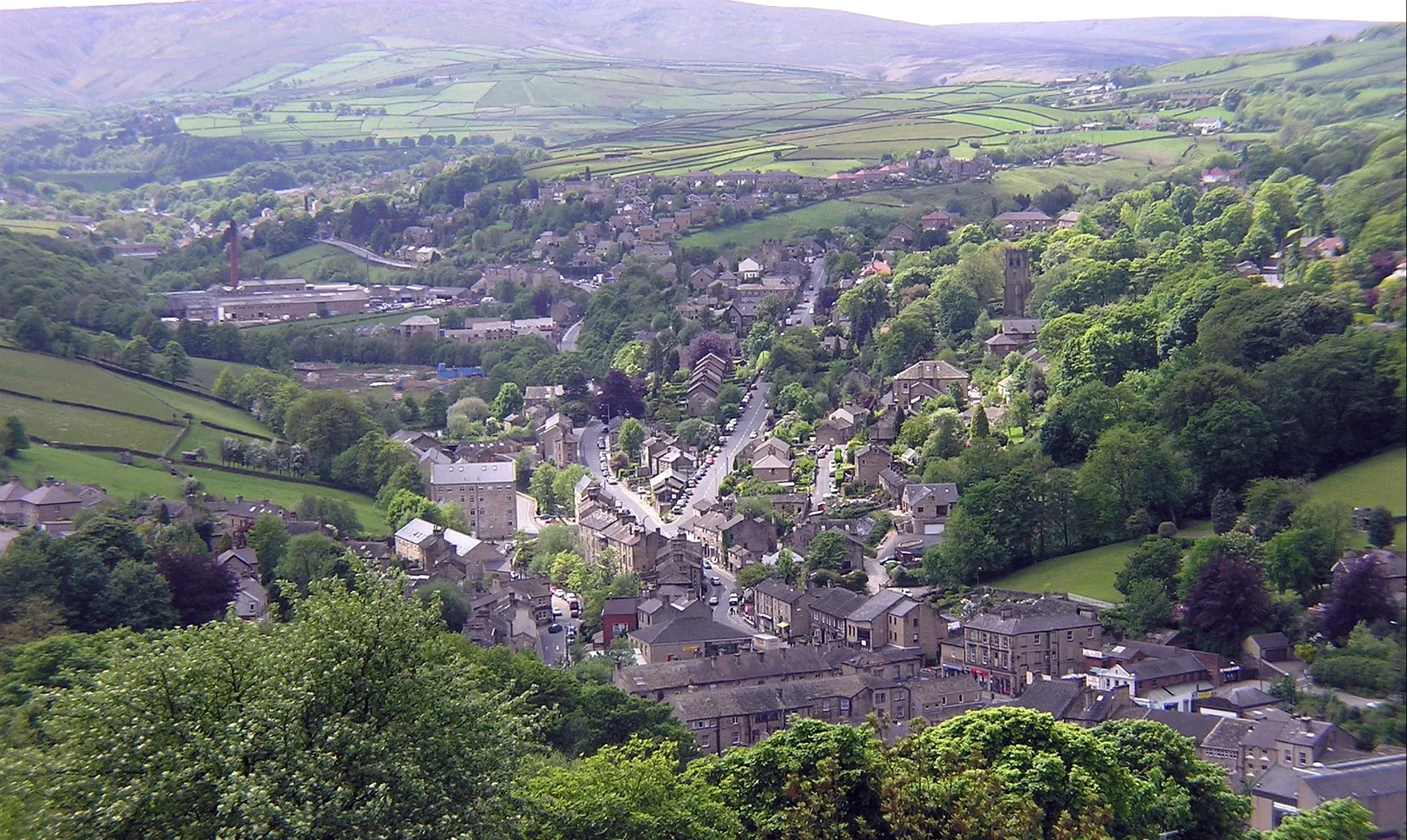 Photo showing: View of Holmfirth from Cliffs above Cliff Road, view is taken facing southwest. The A6024 (Woodhead Road) goes from the centre of the village to the top left of the photo