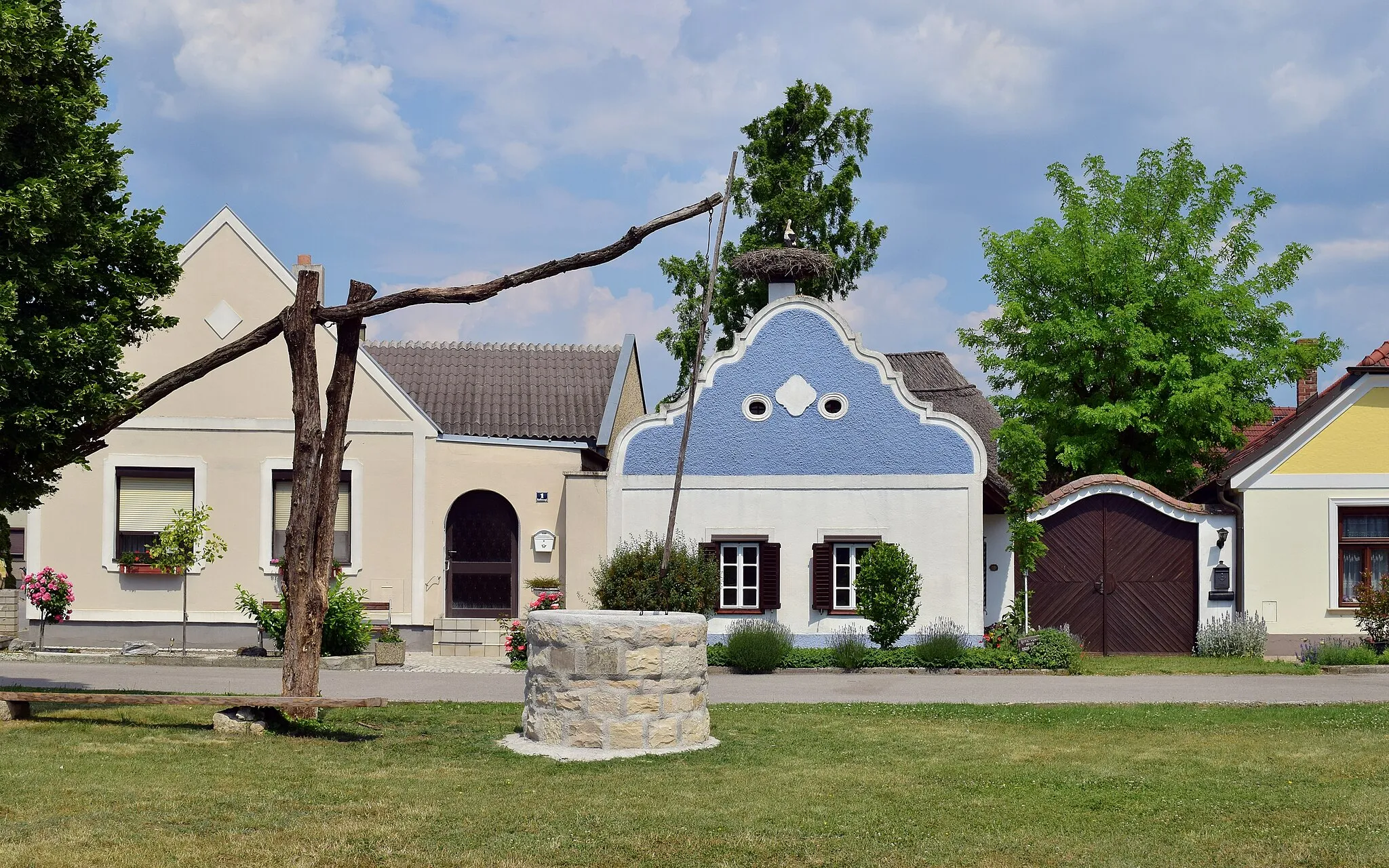 Photo showing: Das auf ein Alter von 250 Jahren geschätzte Hufnaglhaus ist eines der letzten erhaltenen typisch burgenländischen Häuser. Im Dehio wird der barocke Volutengiebel und die Rohrdeckung erwähnt. Das Haus gilt als ein Wahrzeichen der Gemeinde, siehe Das Hufnaglhaus. Der Ziehbrunnen davor wurde im Mai 2021 restauriert und bekam eine Brunnenfassung aus Stein statt zuletzt aus Holz.