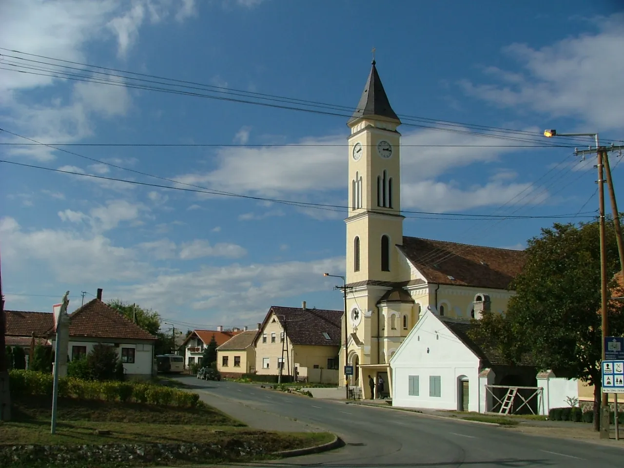 Photo showing: Hegykő; Michael archangel church (local monument) and traditional dwelling house (white, local monument). Front of the church Michael archangel's sculpture (national monument)
